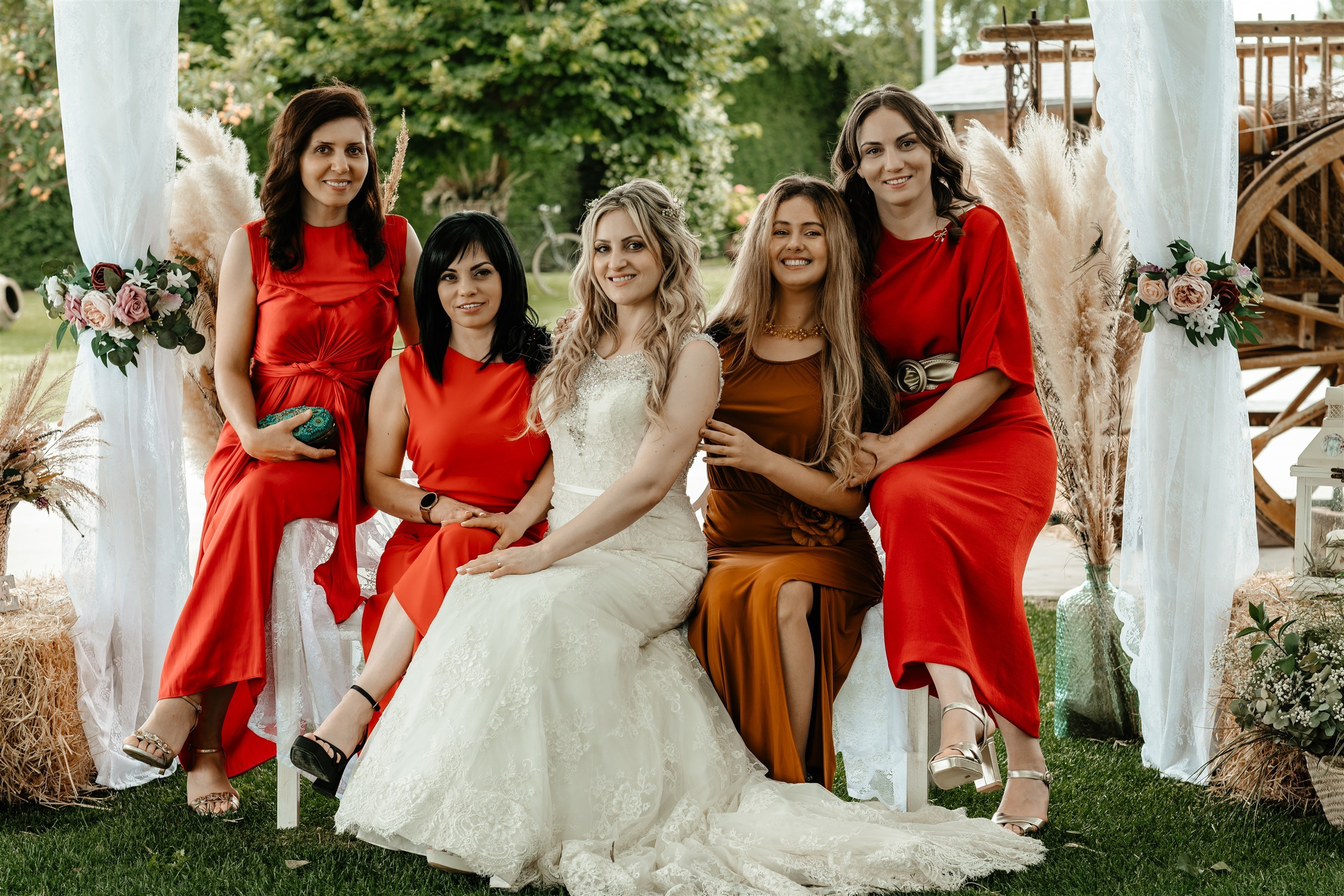 La novia rodeada de invitadas vestidas de rojo, sentadas en el jardín