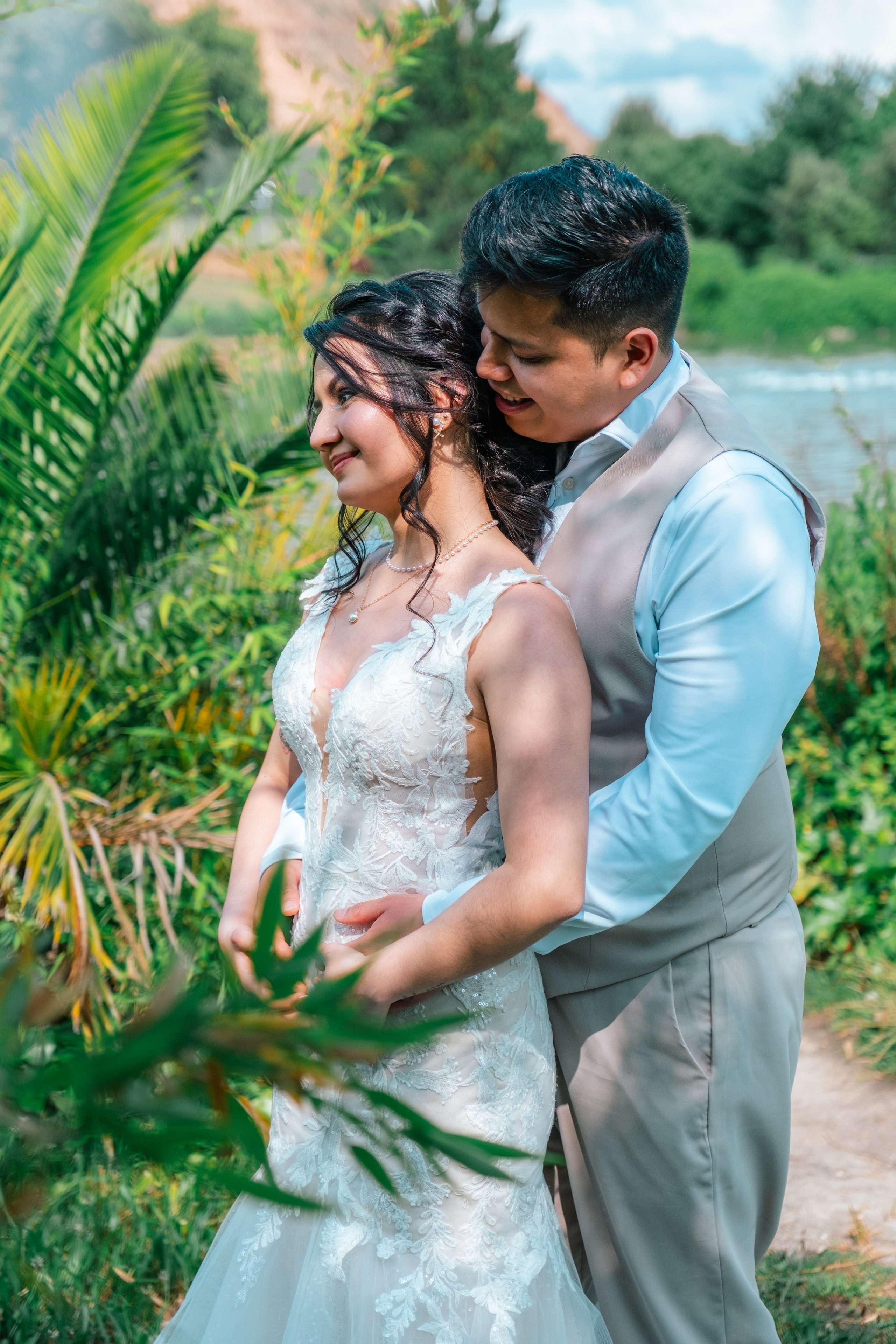 Novio abrazando a la novia por detrás en un jardín