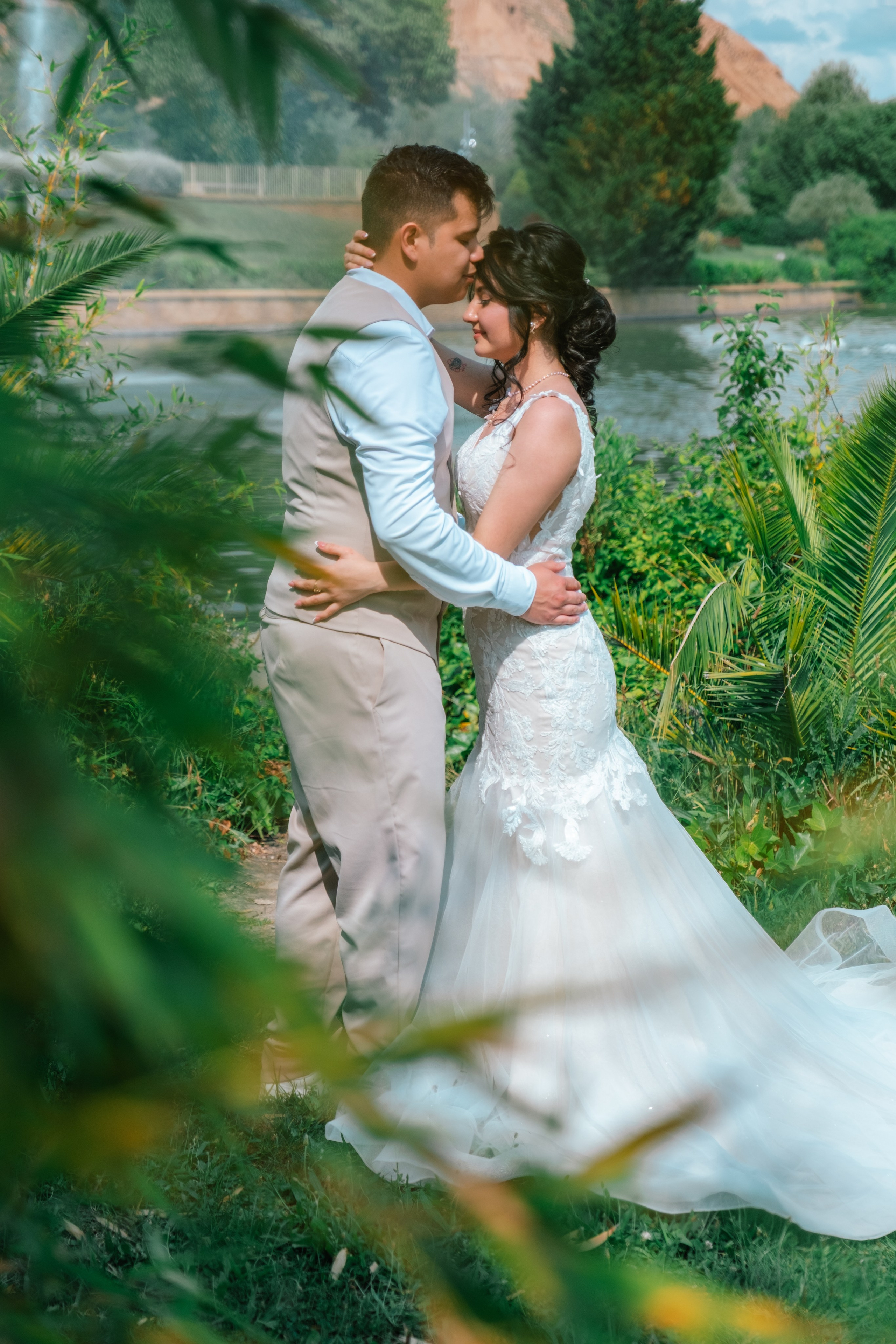 Pareja de novios abrazada entre palmeras durante su sesión de boda