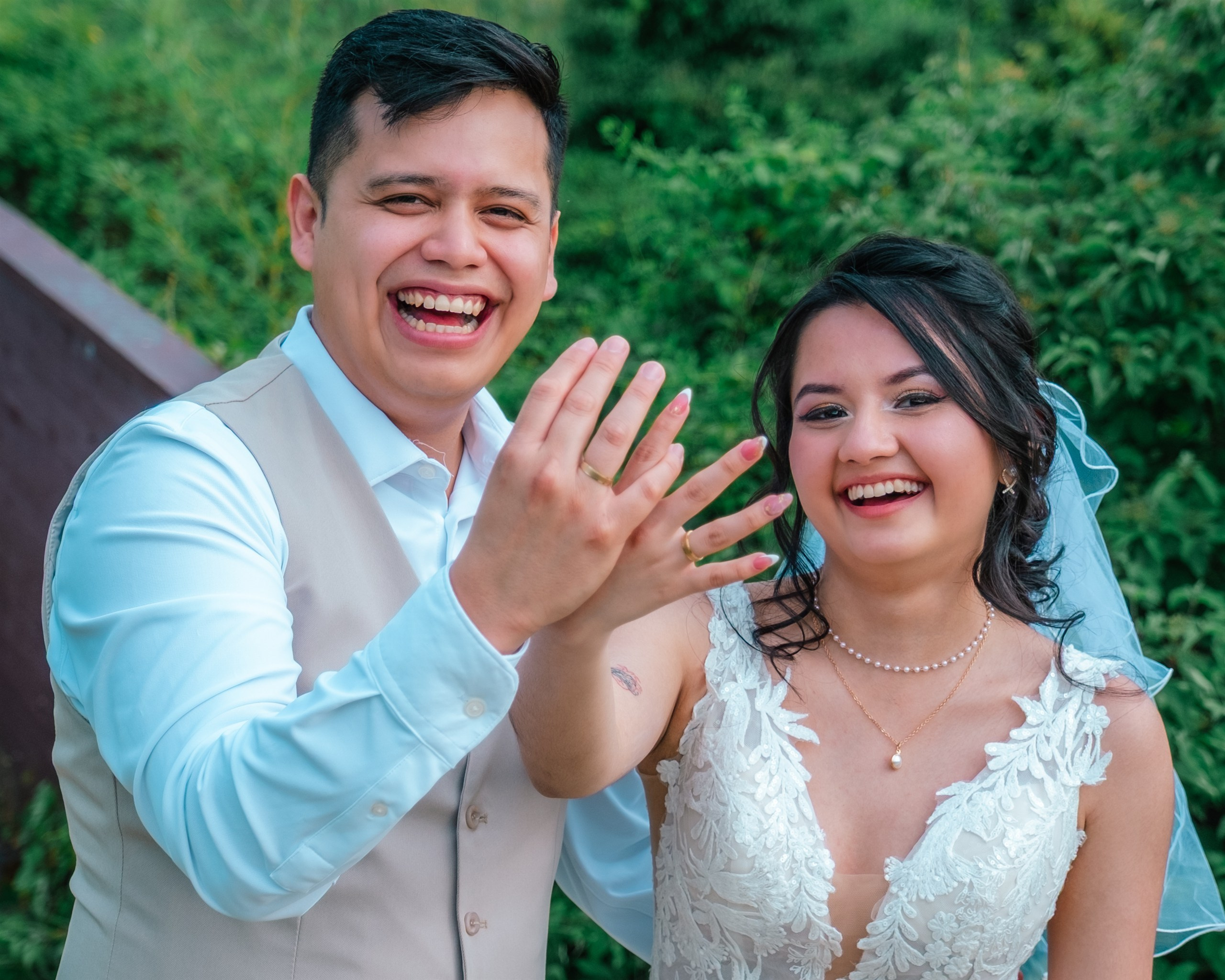 Los novios riendo mientras enseñan los anillos