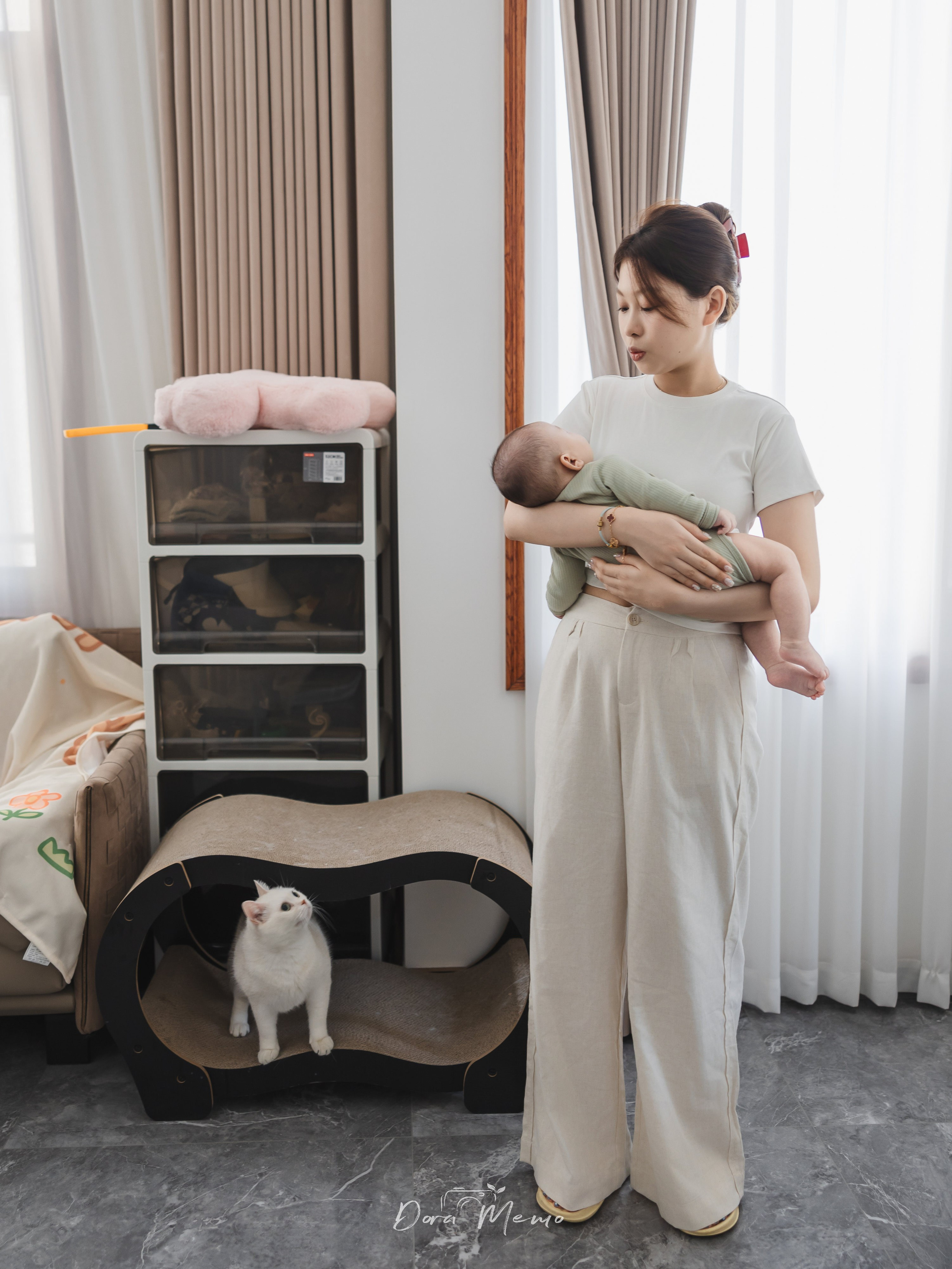 The family cat observes from its tower as mom cuddles the newborn nearby
