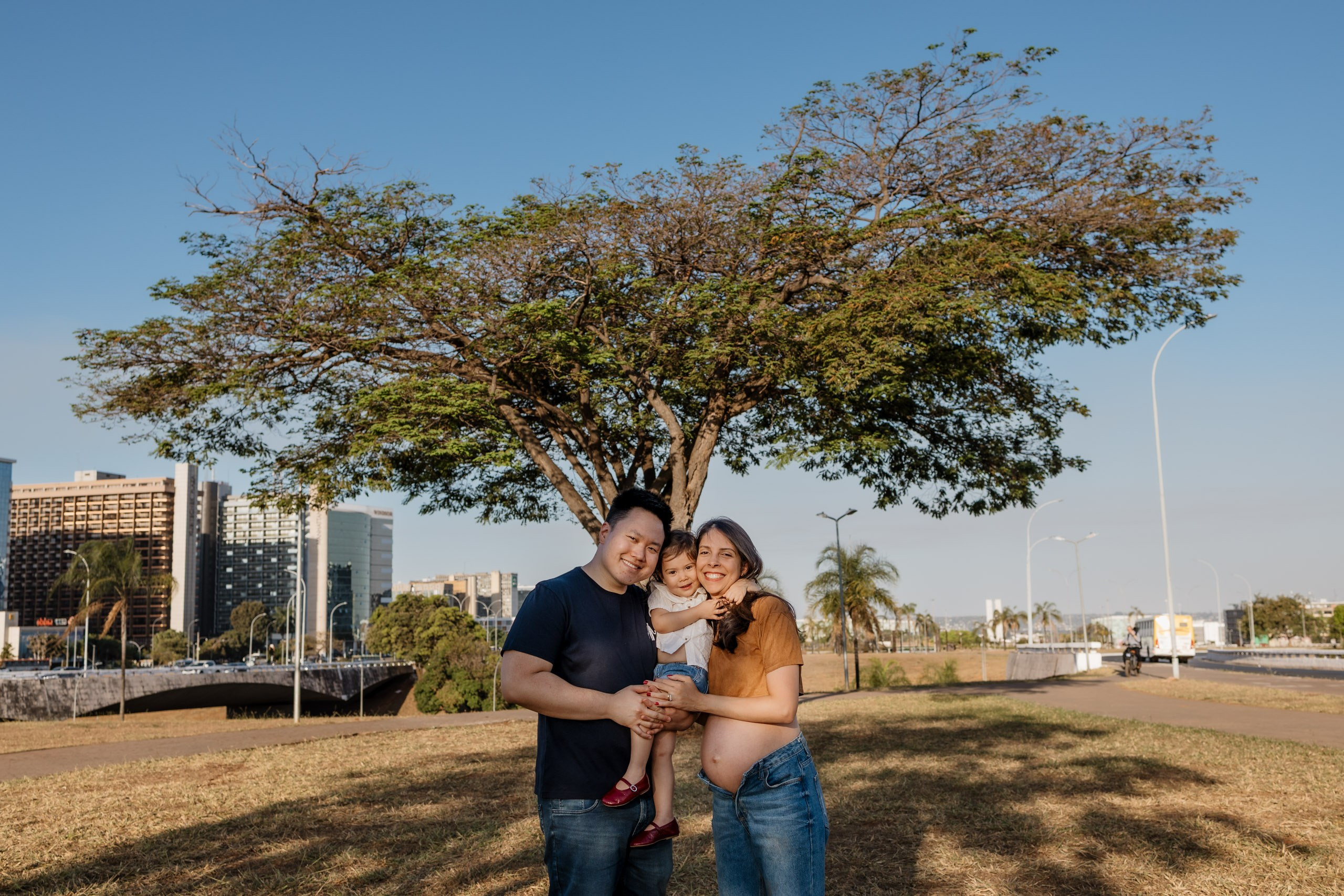 Família brincando em ensaio, com árvore ao fundo