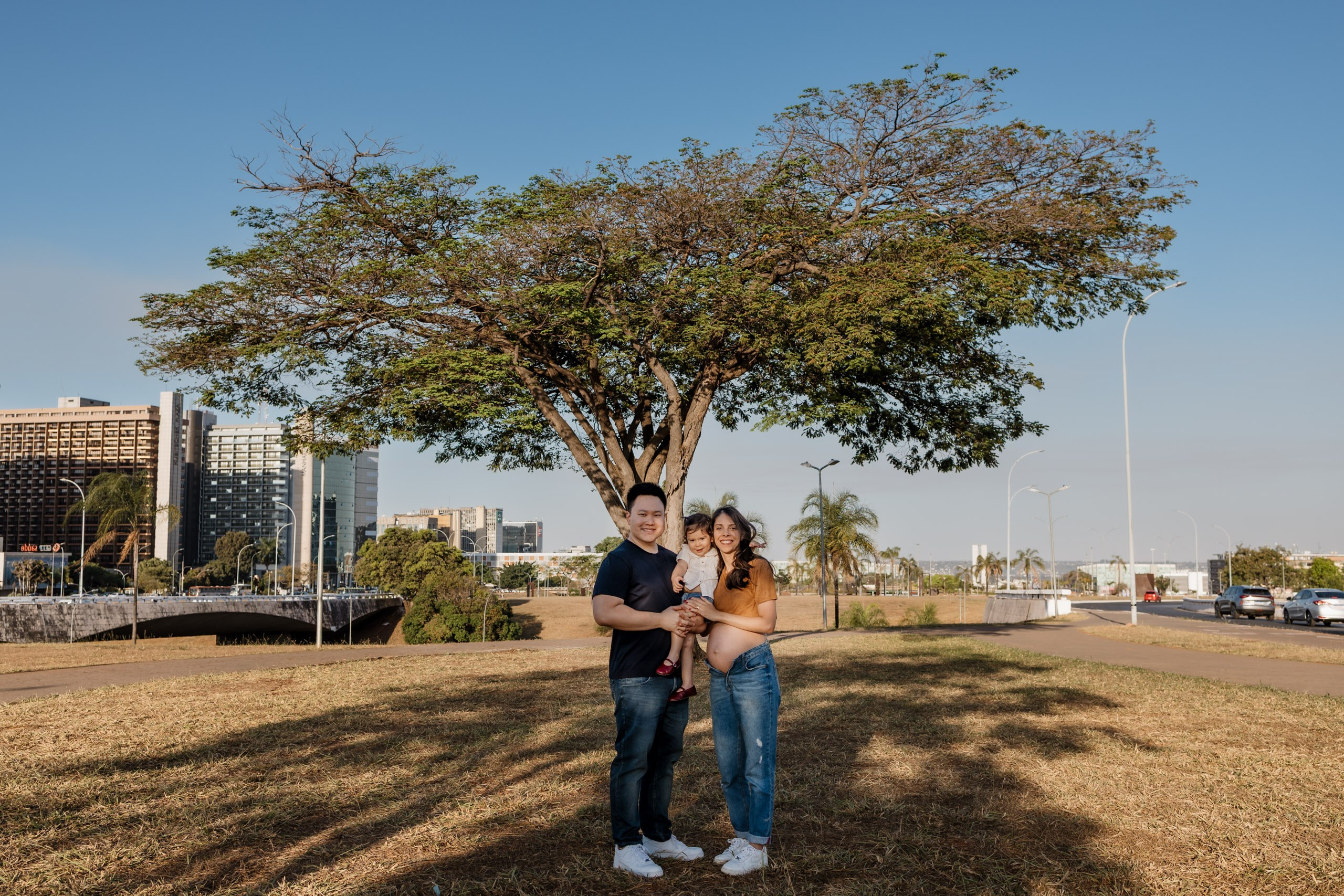 Família em ensaio gestante com árvore ao fundo