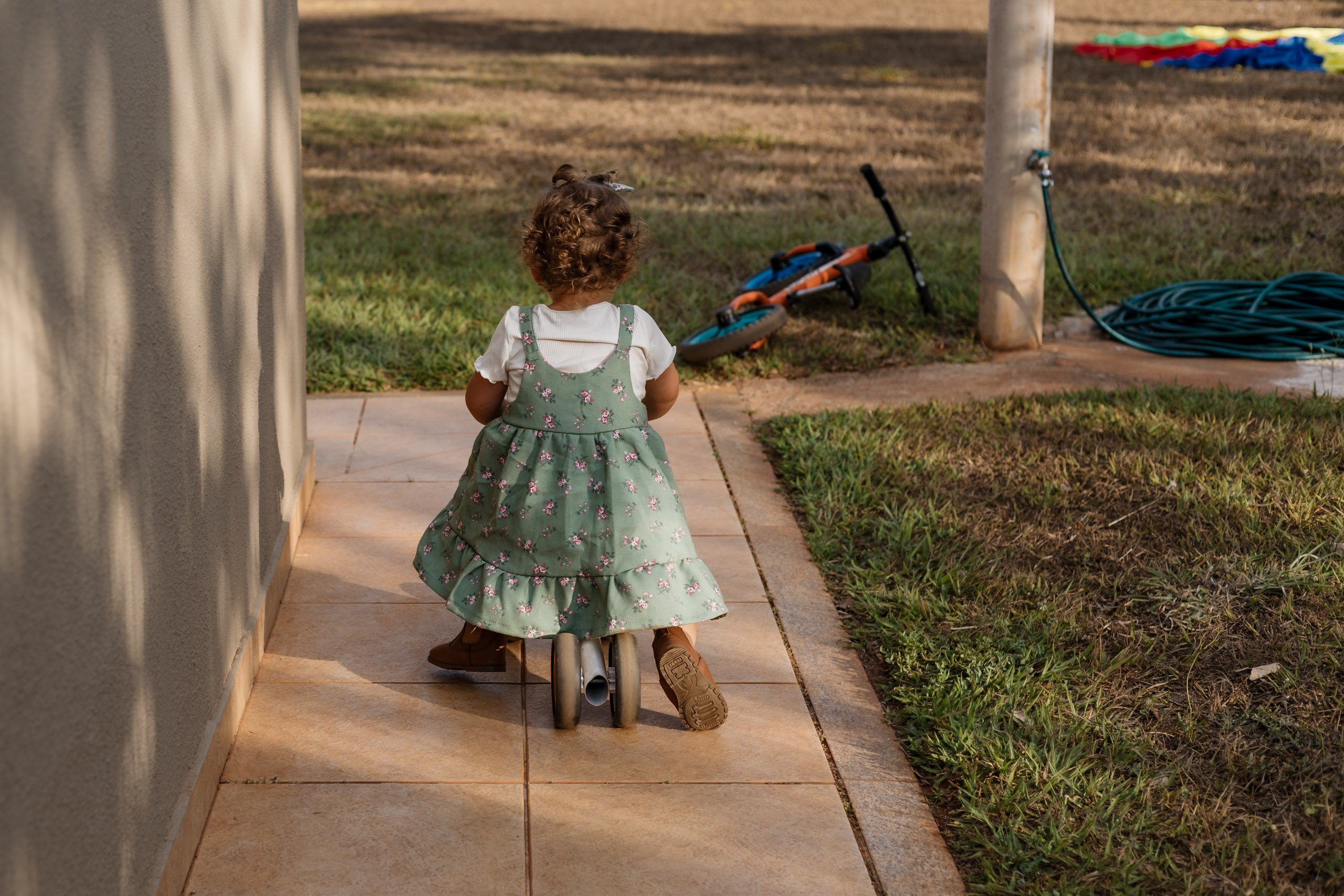 menina brincando com triciclo infantil