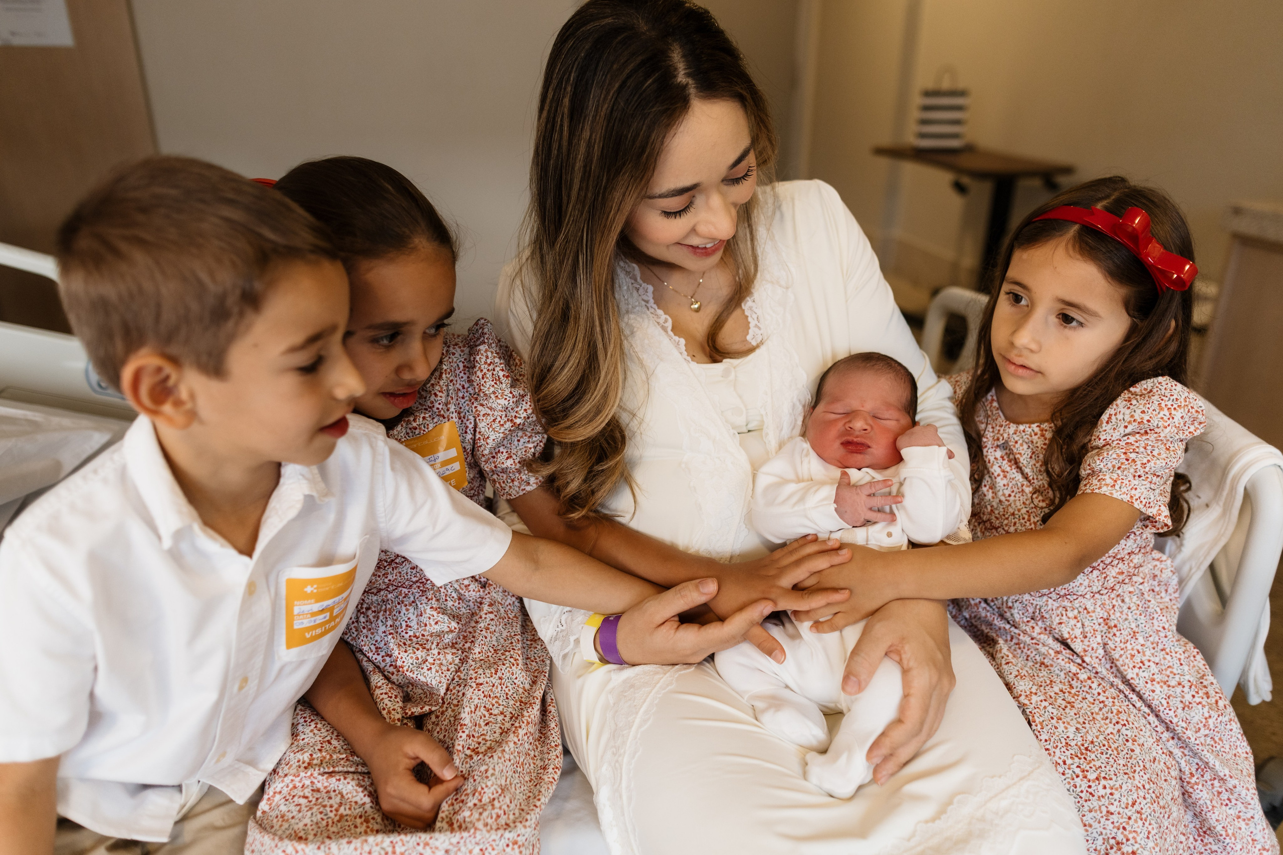 crianças olham irmão mais novo em quarto de maternidade