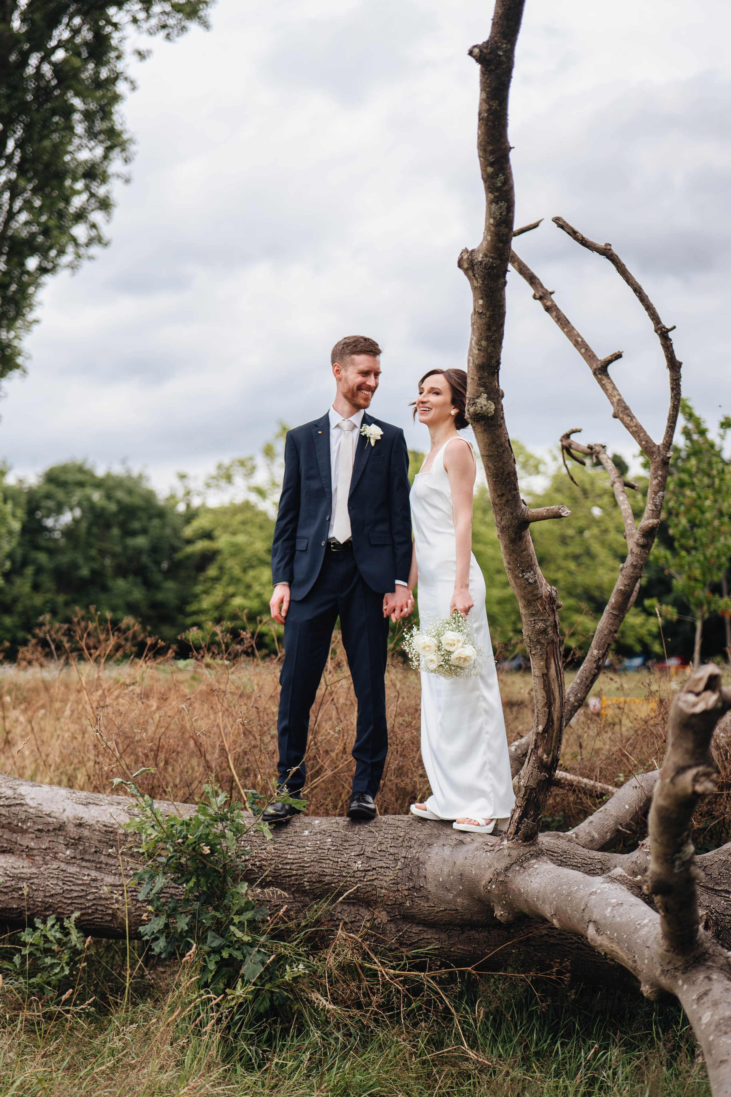 bride and groom posing on the an old dead tree