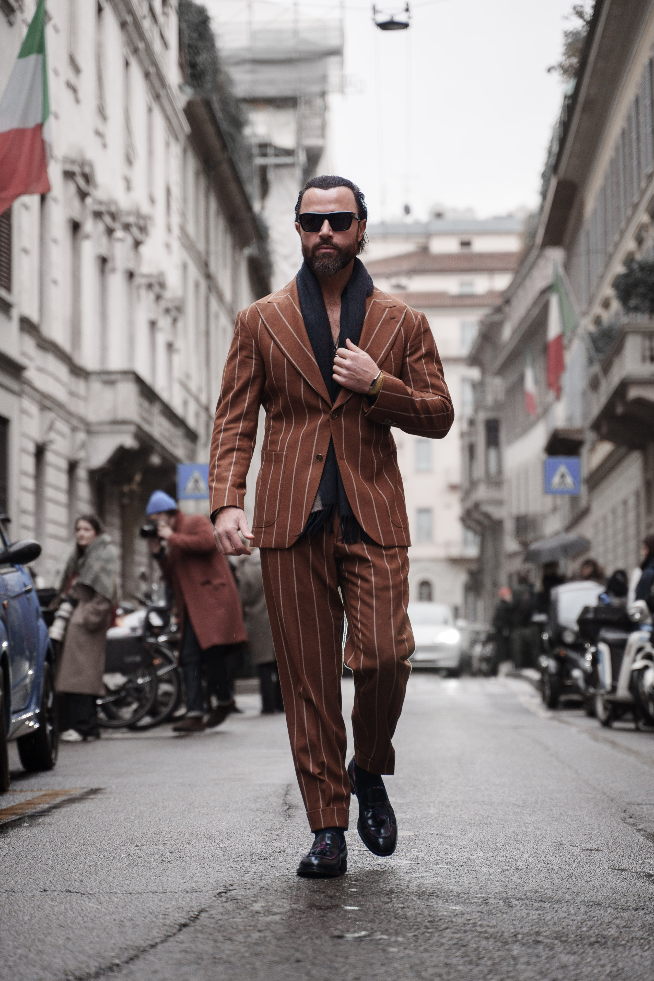 Street style photography in Milan – a man in a brown striped suit walking confidently during Milan Fashion Week