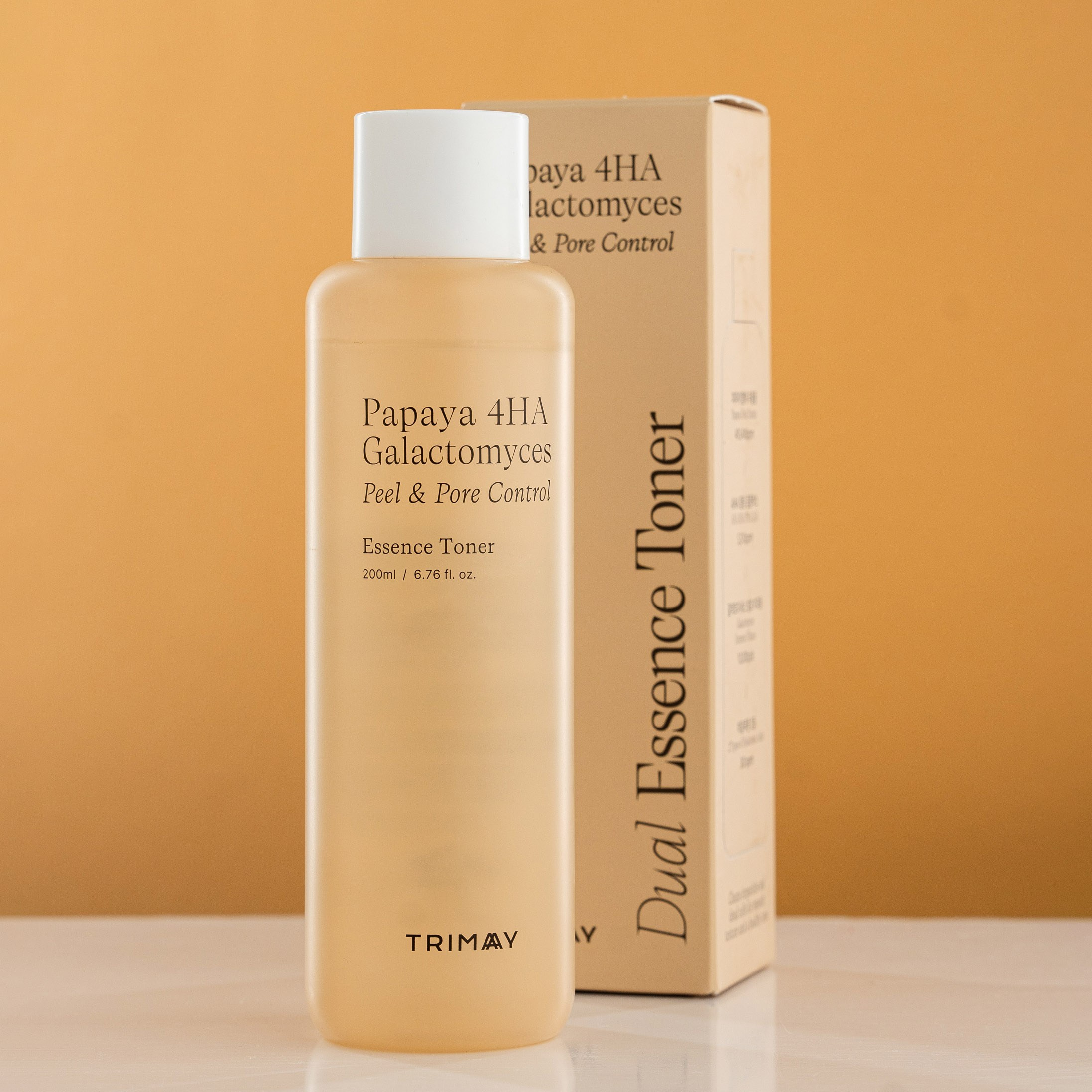 Trimay Papaya 4HA Galactomyces Essence Toner, qutusu ilə birlikdə sarı fonda minimalistik məhsul çəkilişi.