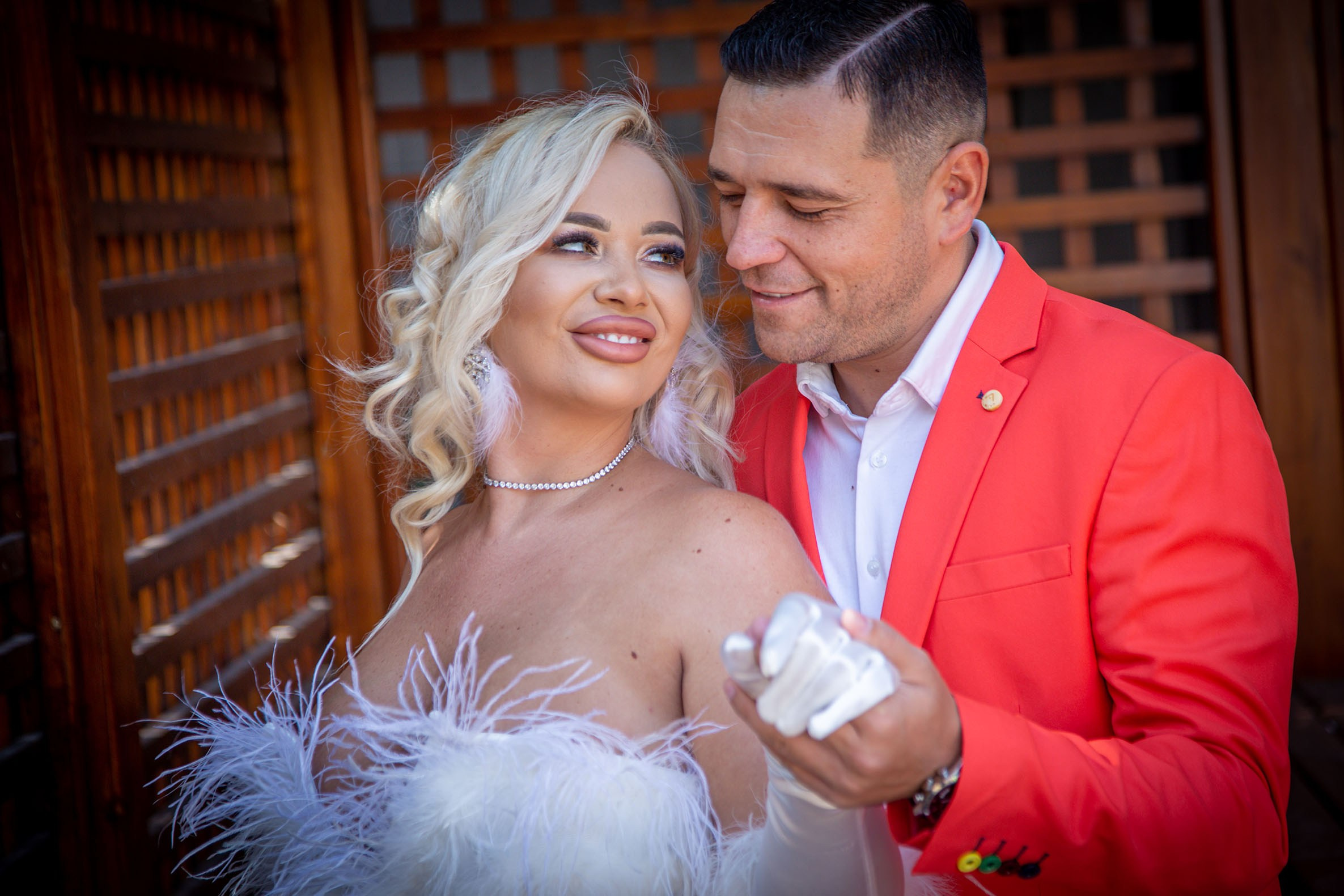 Fotograf nuntă București - Sesiune foto cuplu, mireasa rochie albă cu pene și ginere în costum roșu elegant"
