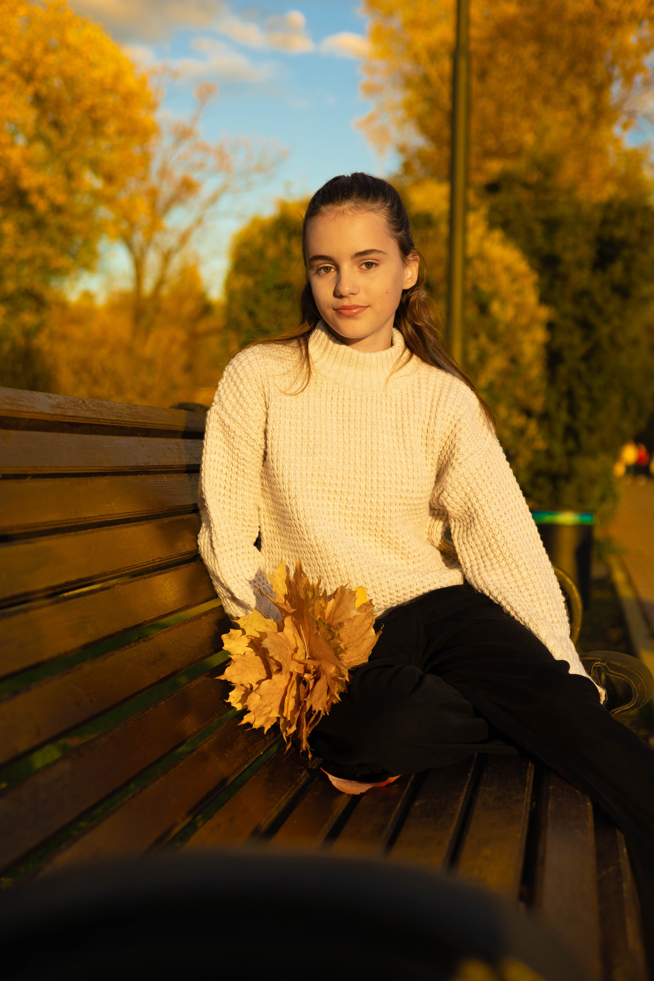 Осенний портрет девушки с букетом листьев в руках.