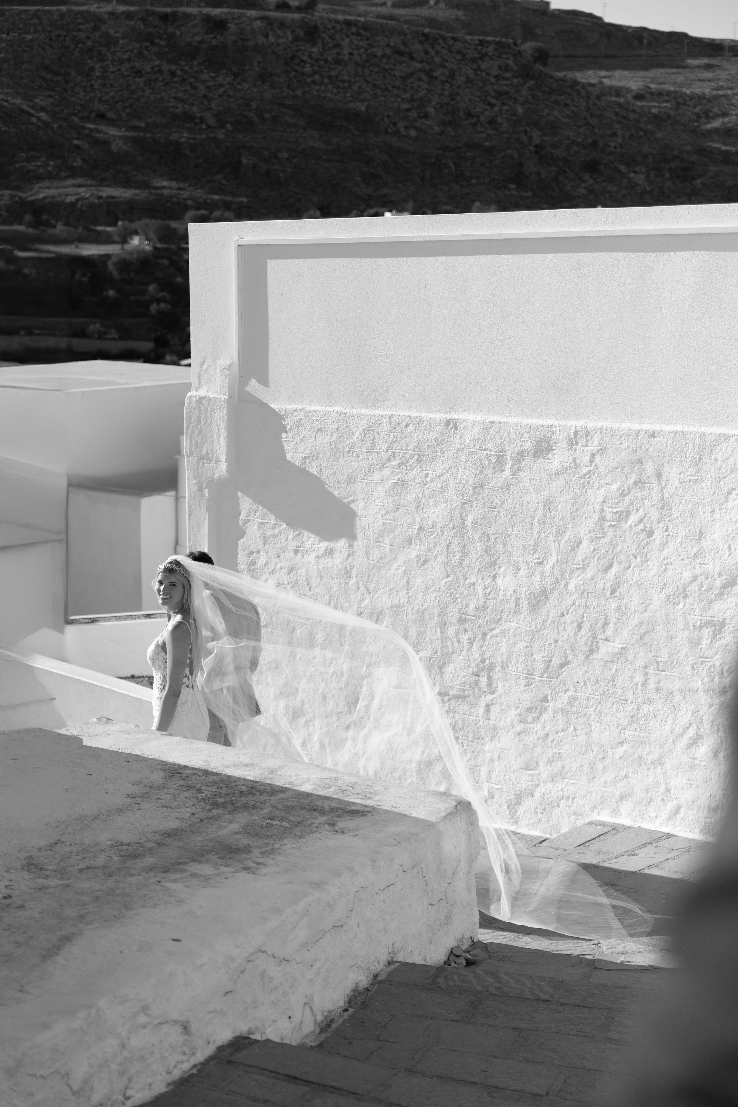 Bride and groom enjoying a quiet moment together on a cobblestone street in Lindos, with traditional Greek architecture around them