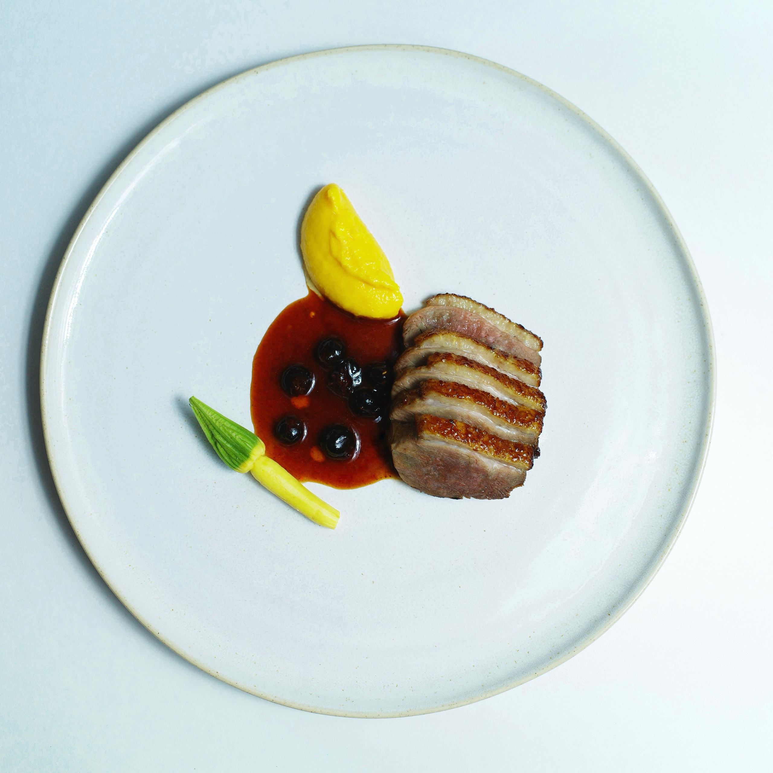 Duck breast with creamy carrot purée and blackcurrant demi-glace.