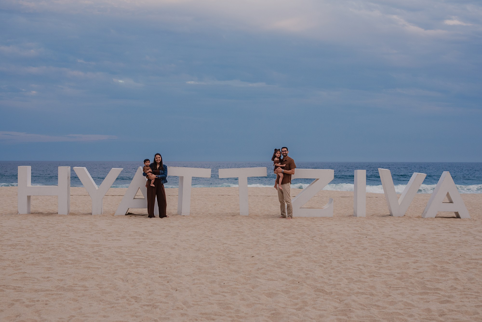 Family silhouette near the Hyatt Ziva Los Cabos beach sign at dusk