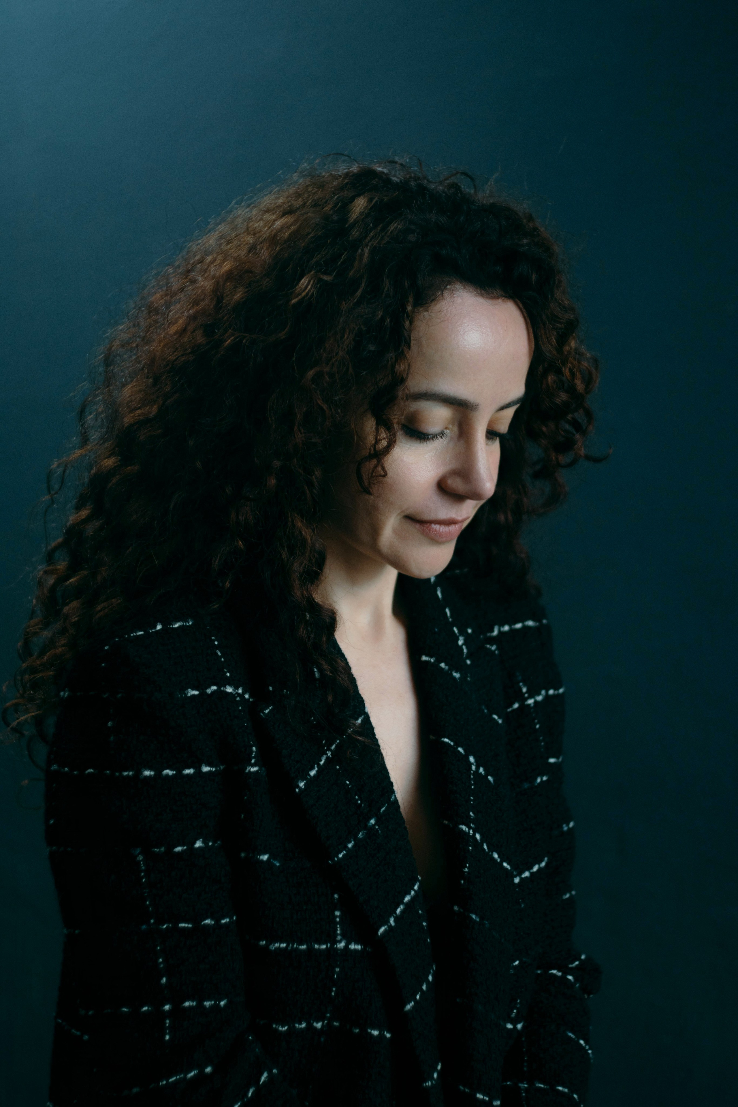 Nachdenkliches Portrait einer Frau mit Locken im Studio – Schwarz trifft Blau