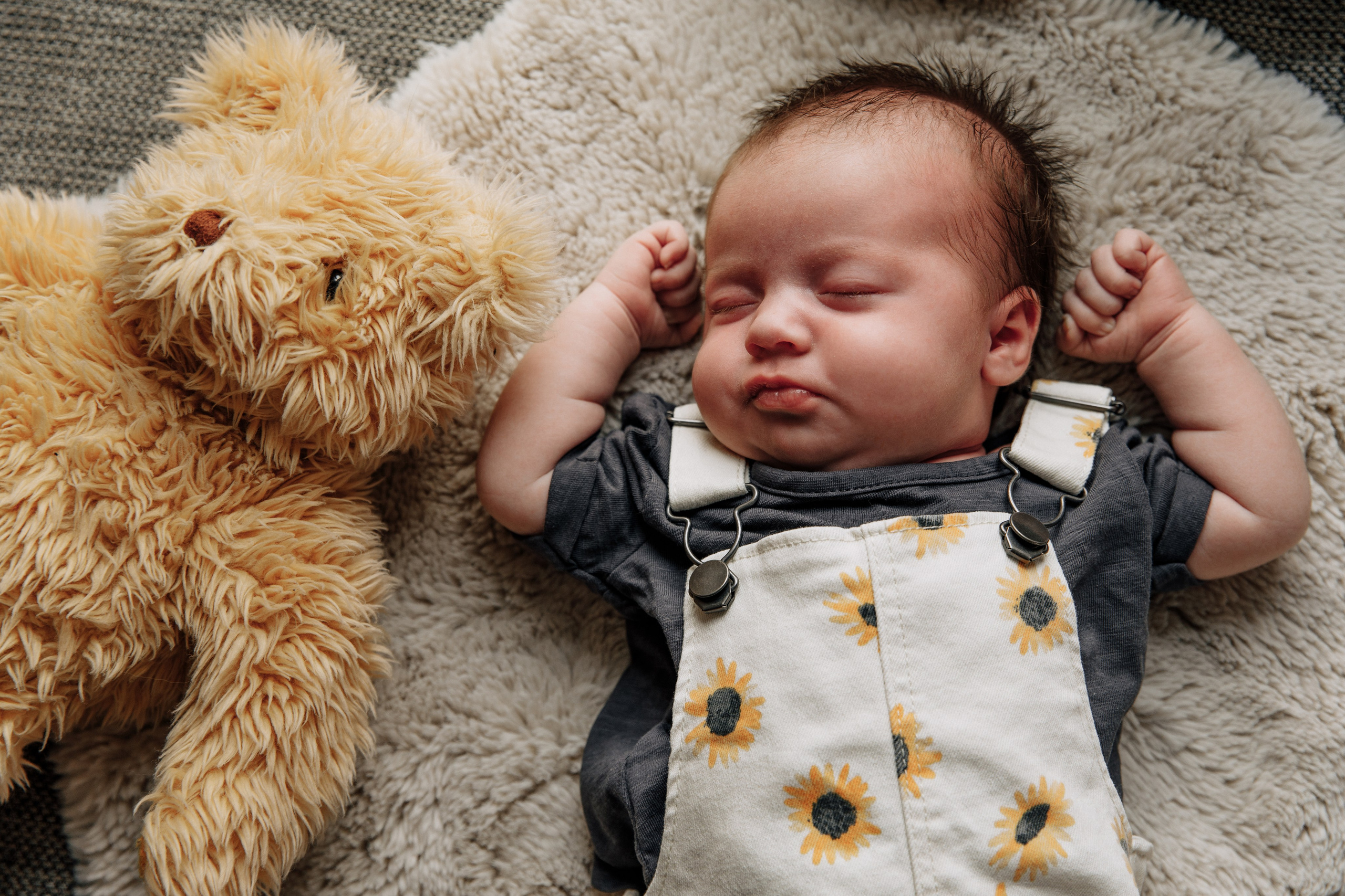 Baby liegt gemütlich neben seinem geliebten Plüschbären.