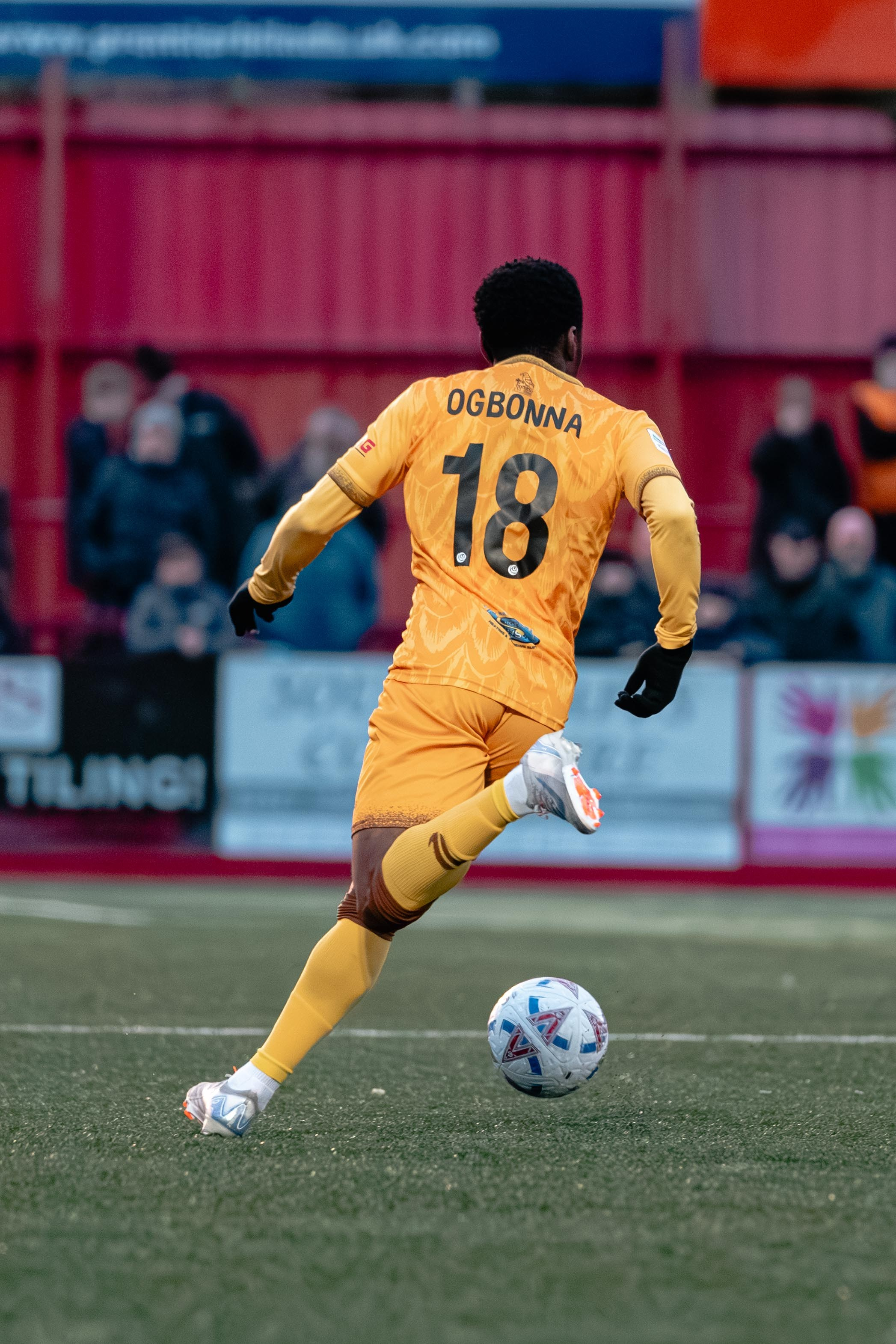 Sutton United No. 18 Ogbonna carries the ball forward during open play.