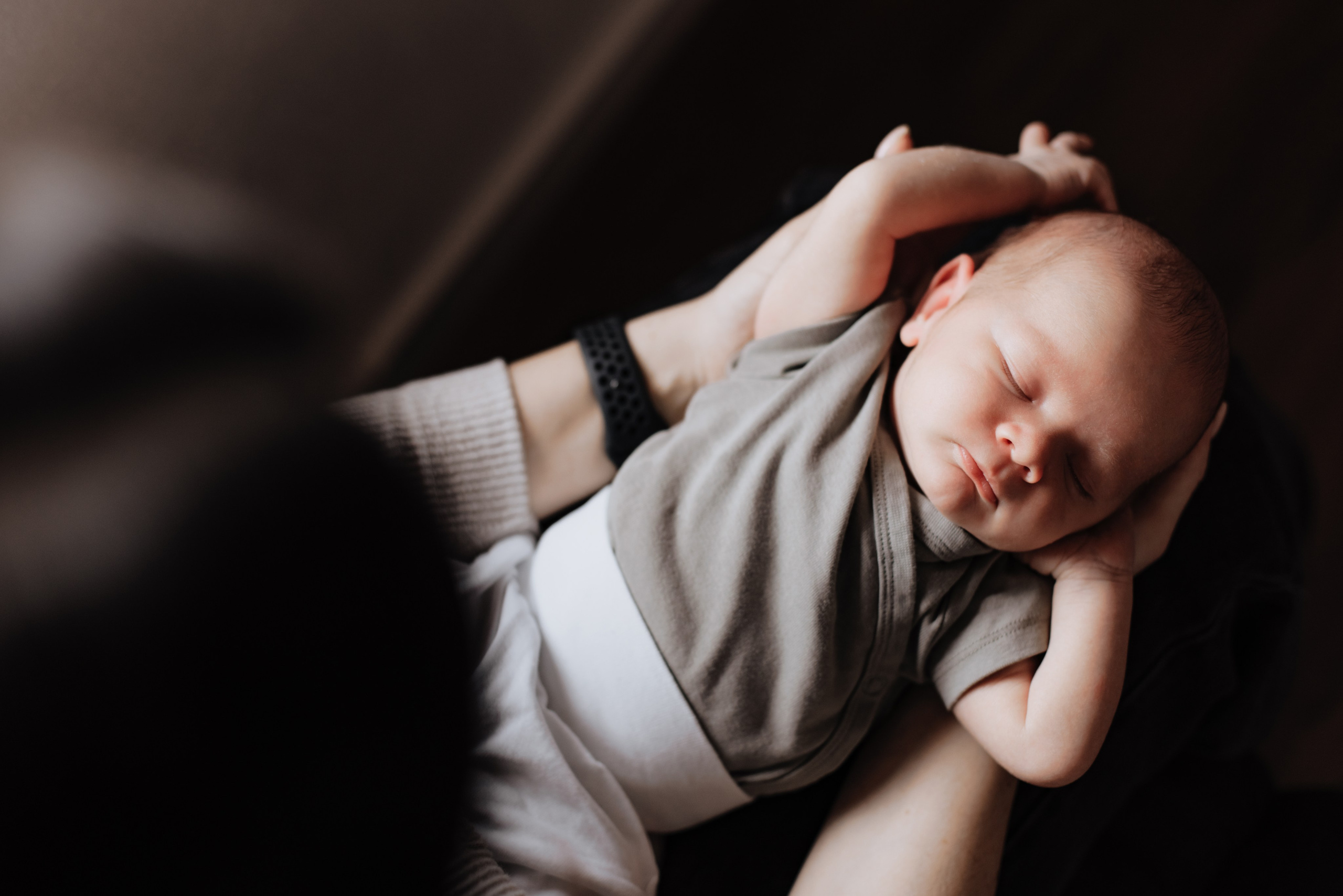 Baby liegt auf den Armen der Mutter und zieht sich hoch. Ein liebevoller und zärtlicher Moment.