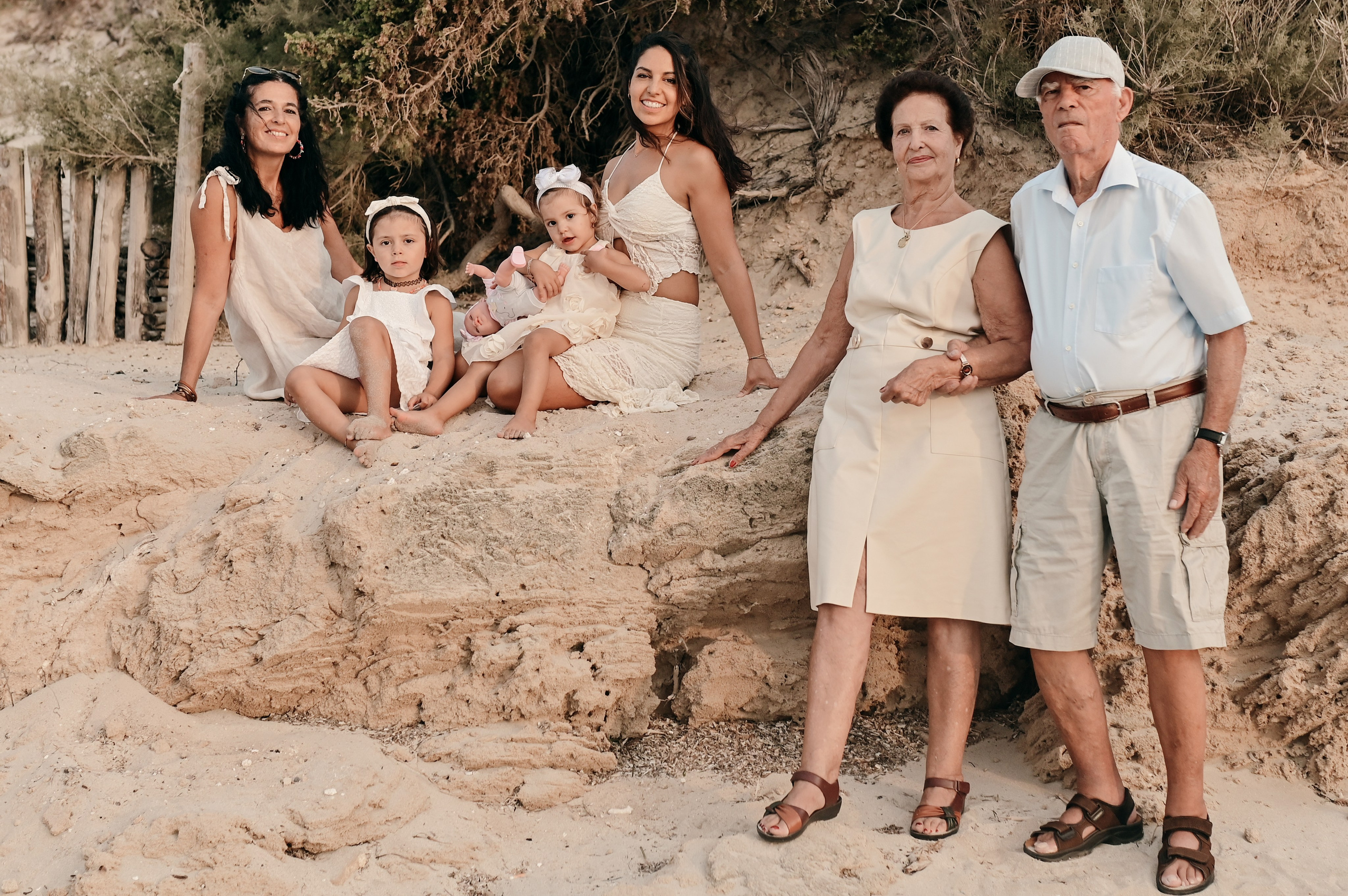 Extended family with grandparents, parents, and children enjoying a summer moment by the rocks during a family photoshoot in Puglia.