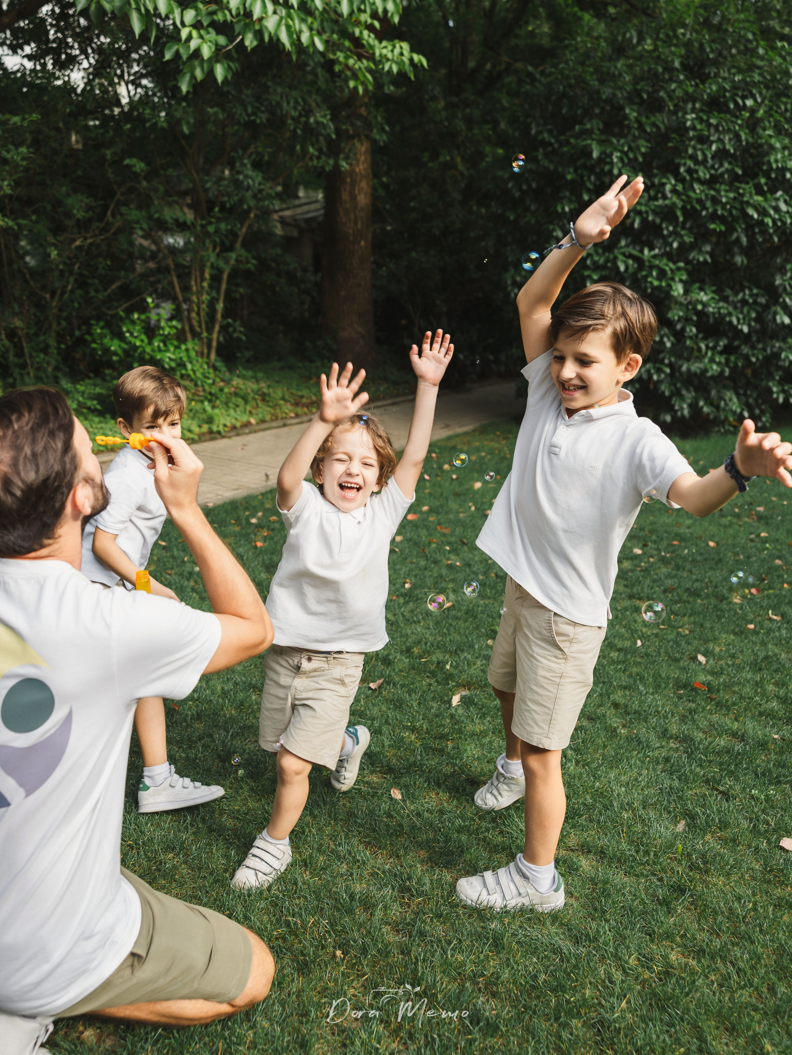 Dad blowing bubbles for three kids | Father blowing soap bubbles while his children chase them in the garden