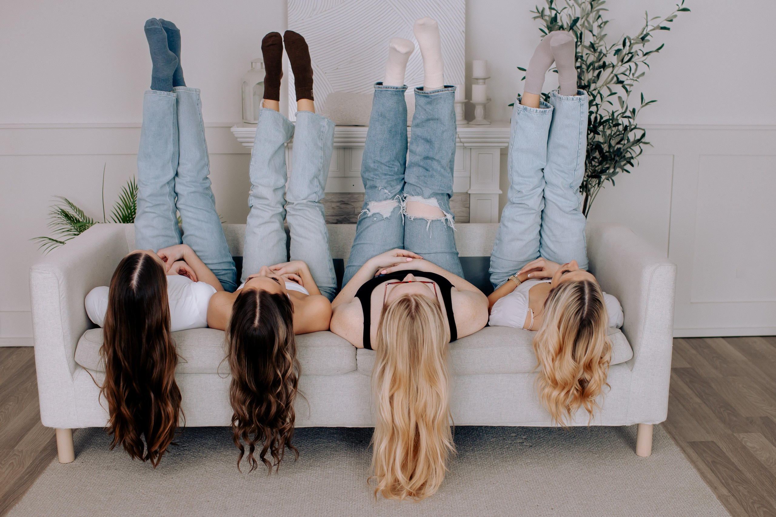 4 women laying on a coach with long hair hanging down, ad for a hair salon