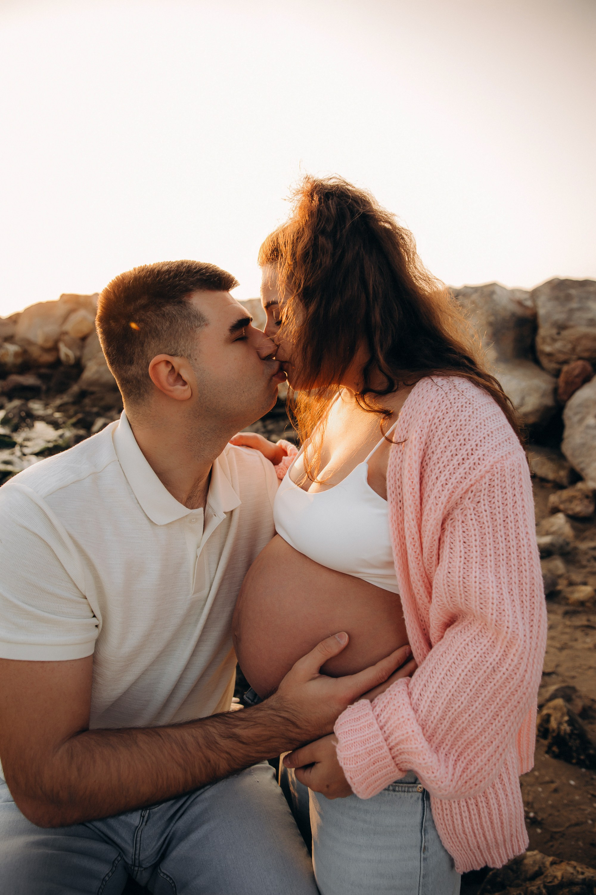 Sesión de fotos de embarazo en Valencia, España, con una pareja abrazándose en un entorno acogedor e íntimo con la barriga de embarazada visible, resaltando la conexión y la espera — ideal para sesiones maternity, sesiones de embarazo en pareja y fotografía familiar en Valencia y en toda España.