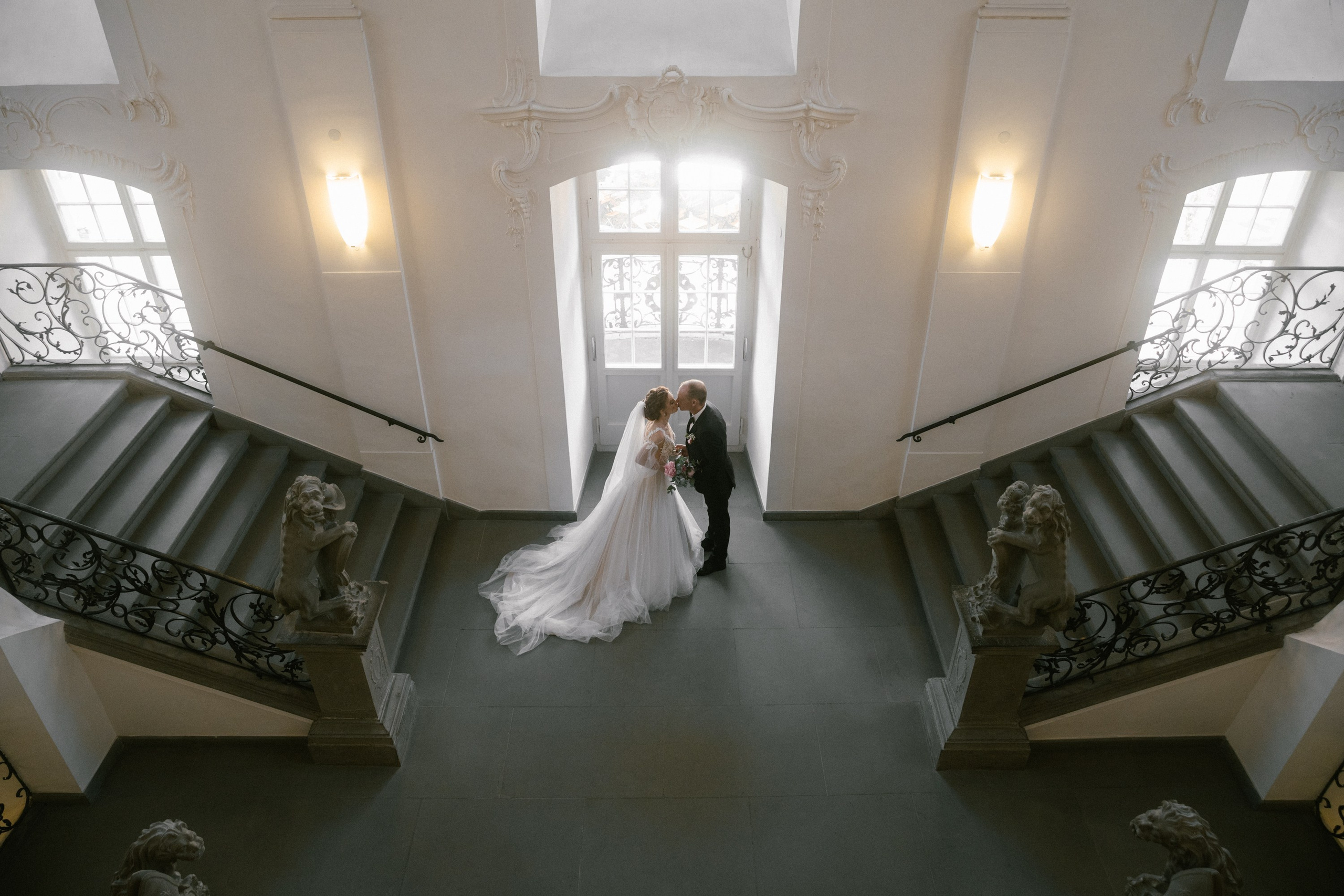 Bride and groom kiss near baroque staircase at Schloss Meersburg in soft light