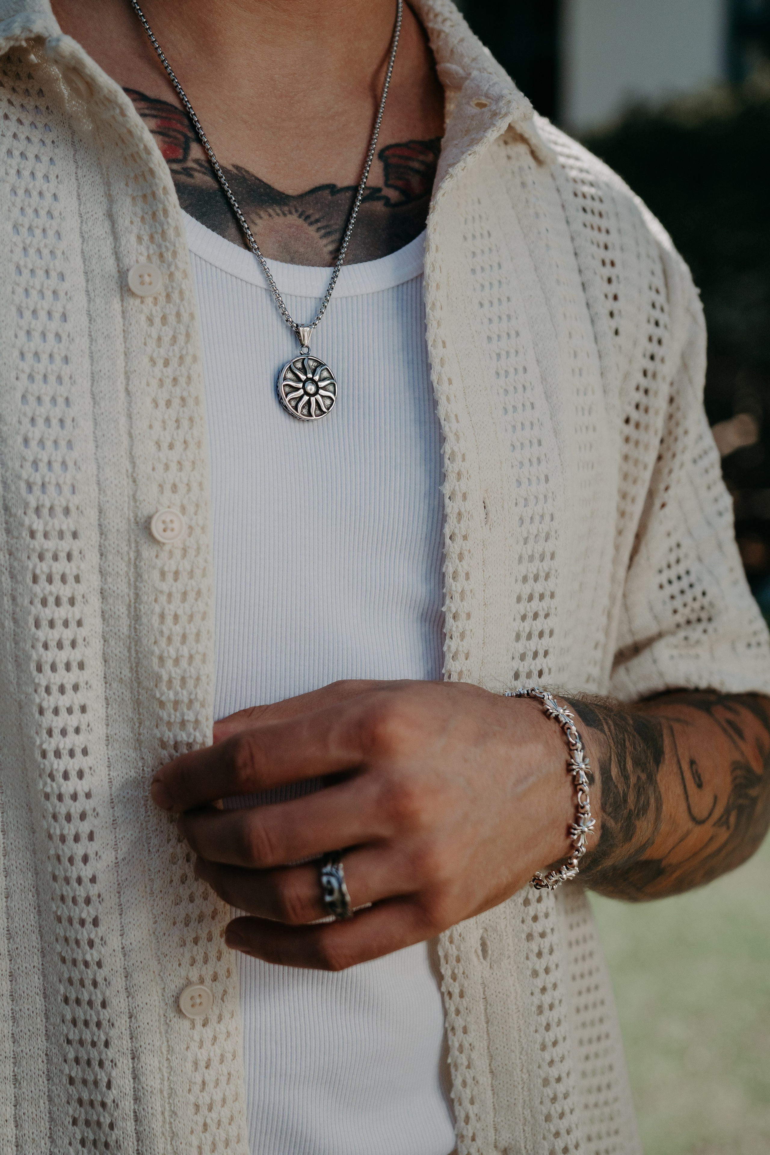 Tattooed model styling silver jewelry with a casual outfit, highlighting urban fashion.