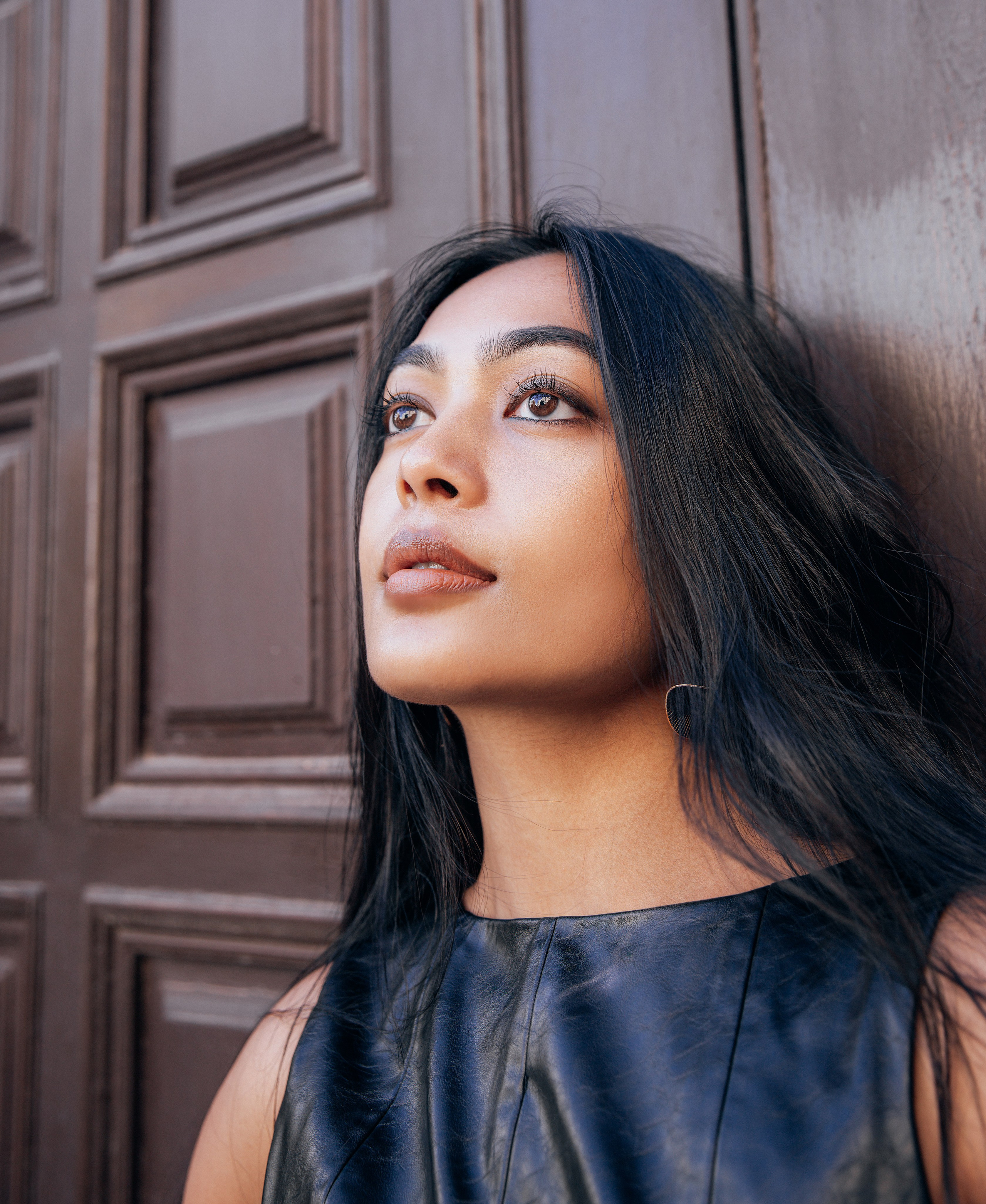 Крупный женский портрет, снятый в Валенсии, Испания — женщина с выразительными глазами и натуральным макияжем на фоне фактурной деревянной двери. Идеально для демонстрации элегантной и чувственной женской портретной фотосъемки в Валенсии и по всей Испании.