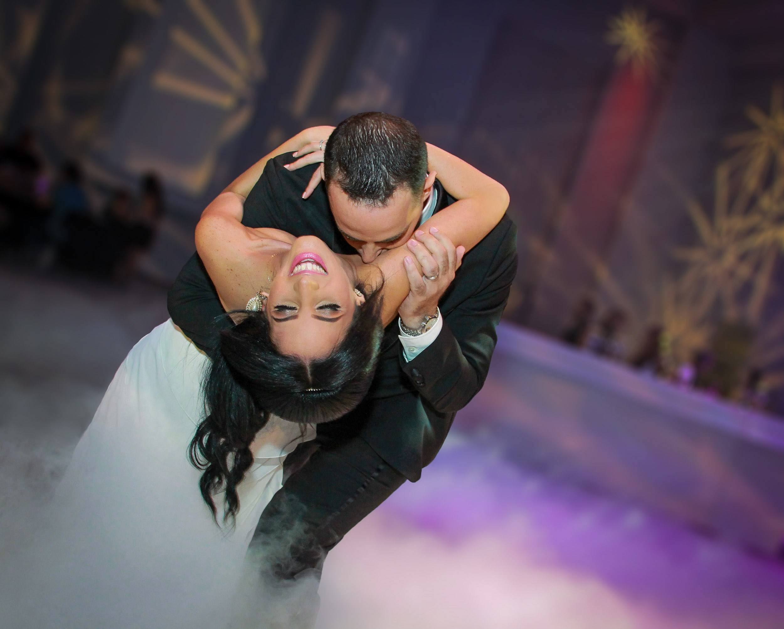 Bride and groom kissing during their first dance surrounded by low fog at a wedding reception in Israel