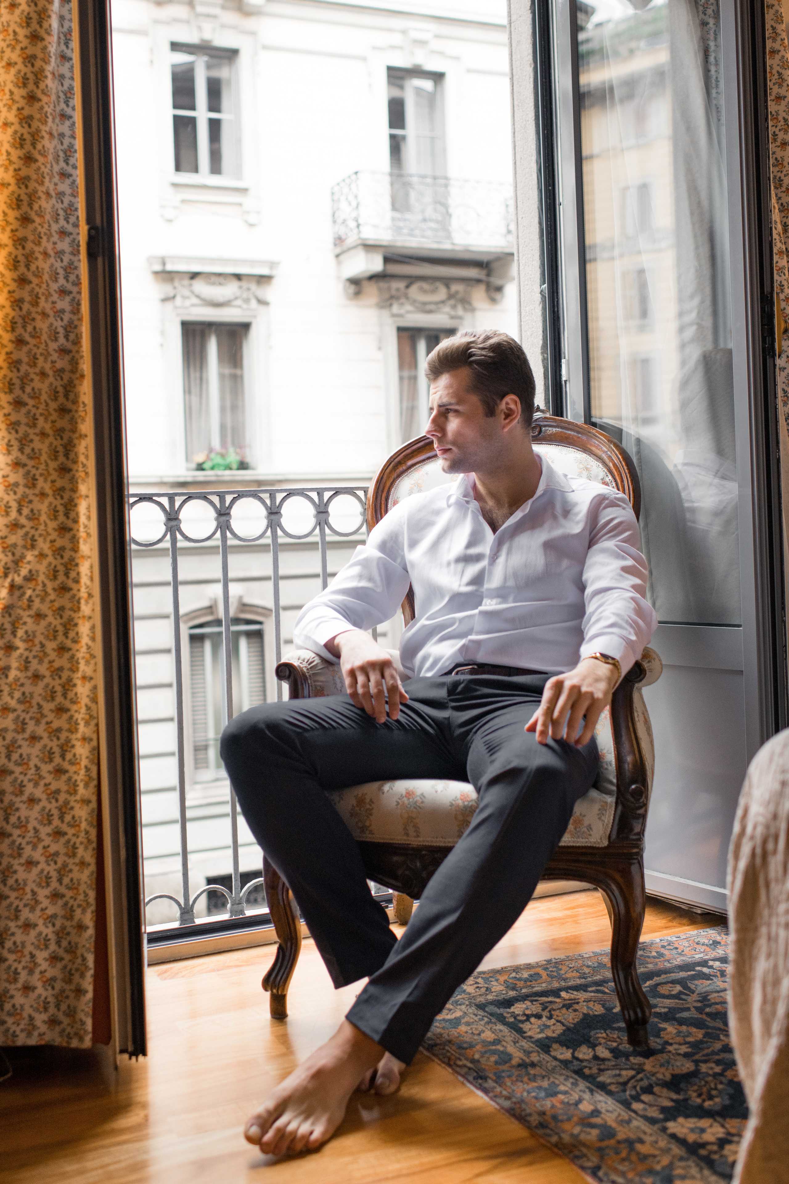 A fiance siting in the chair and waiting on the balcony for his bride in Milan, Italy