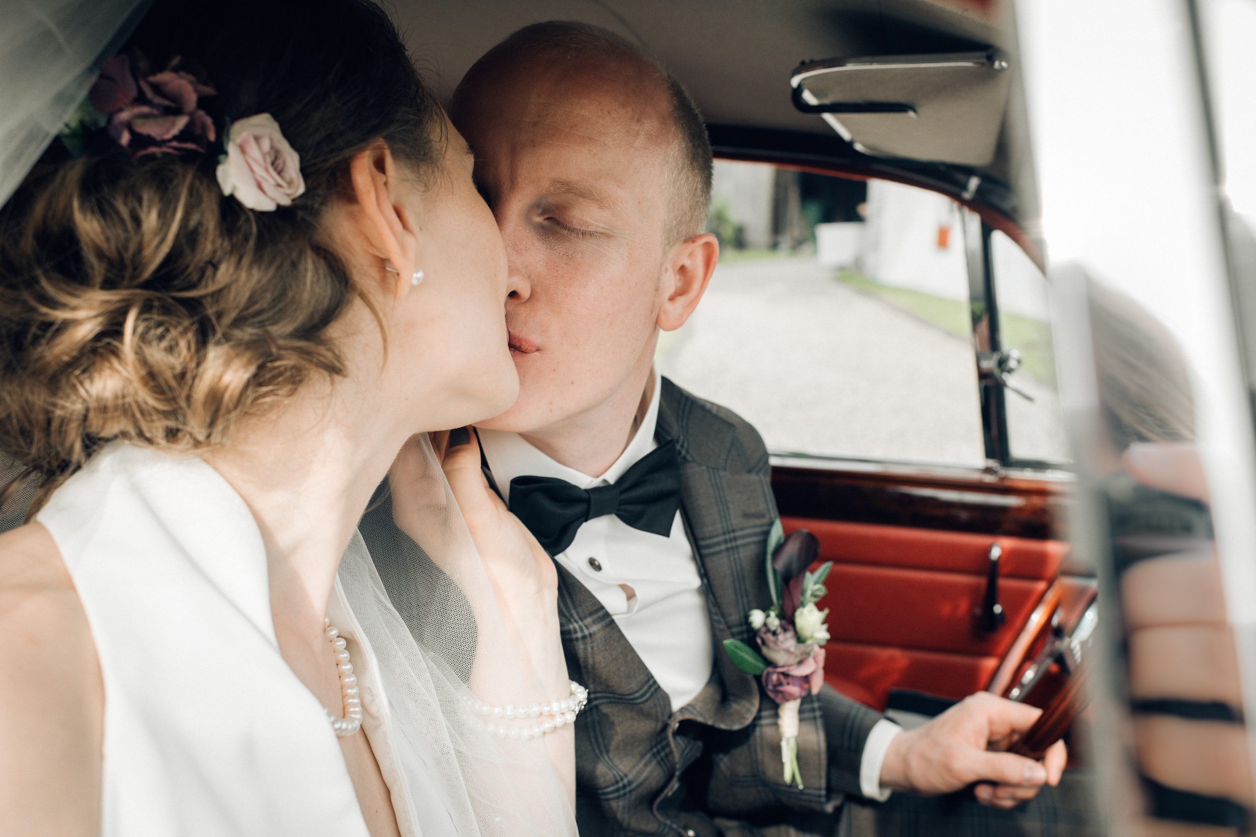 A bride and a groom kissing in an old timer on a wedding day