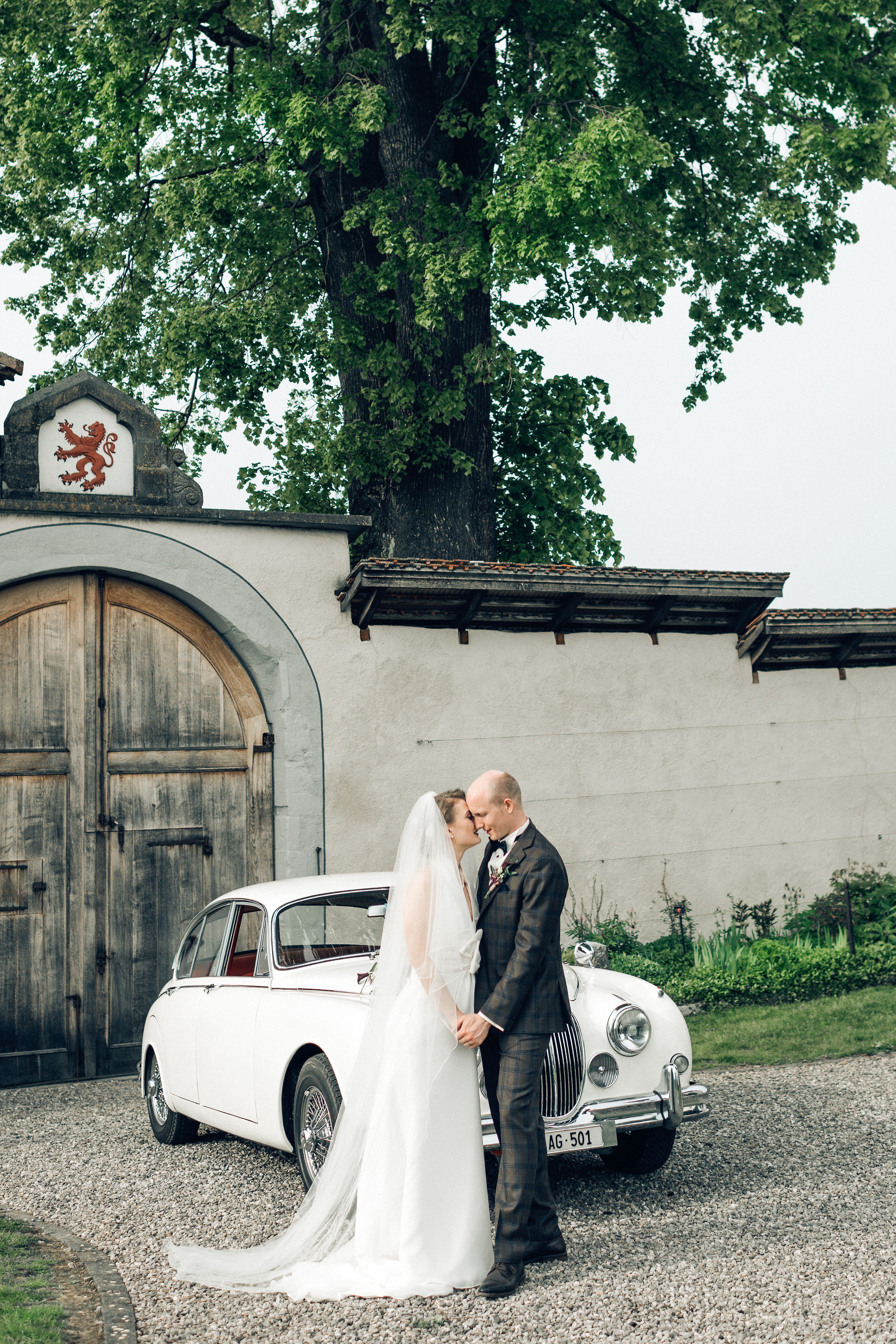 A wedding couple in wedding dresses near an old timer