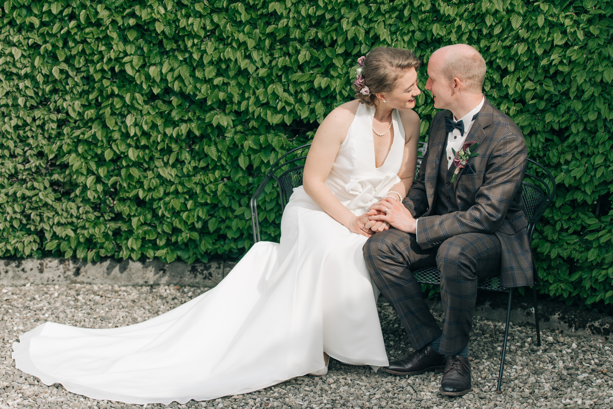 A wedding couple on a bench in a garden
