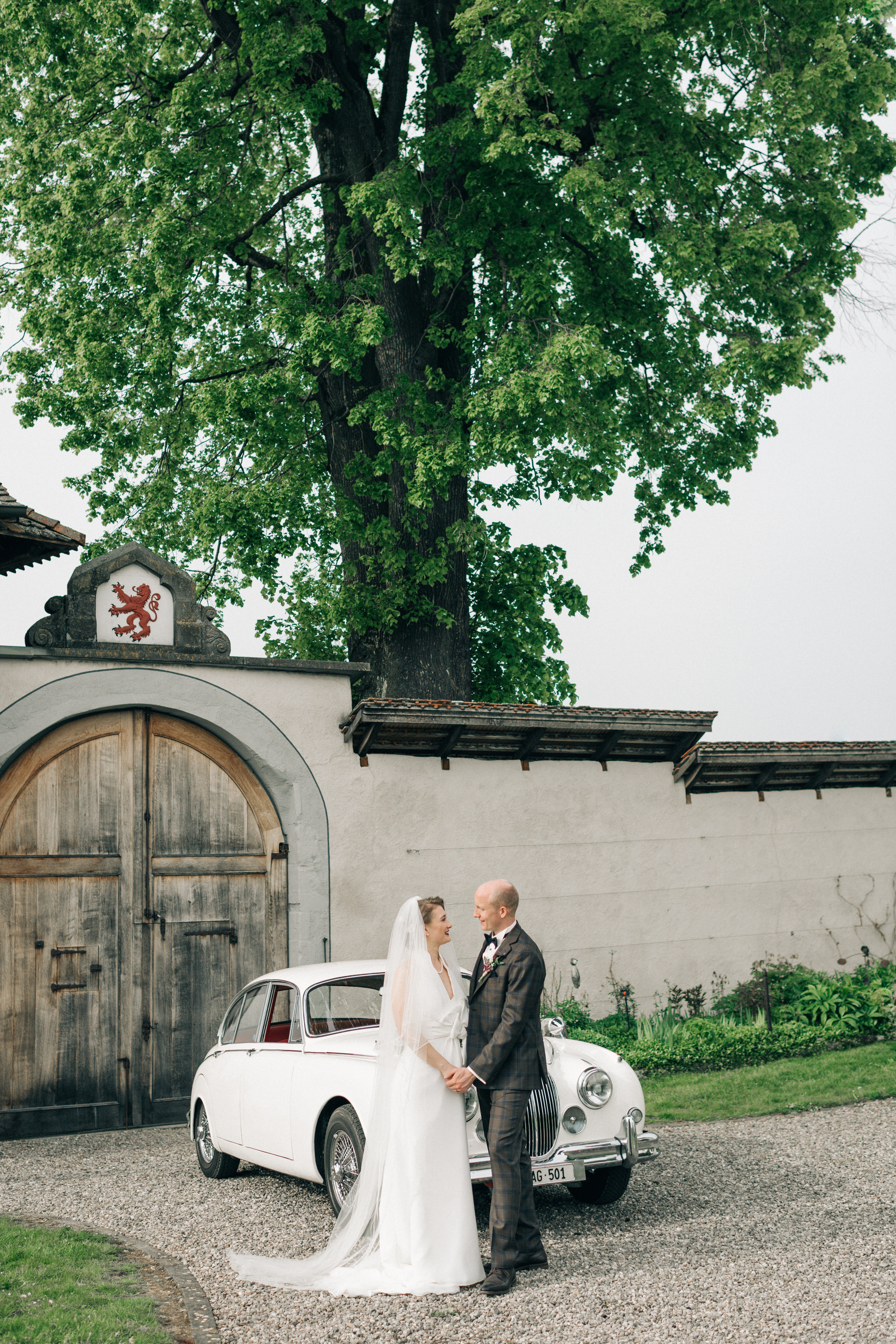 A wedding couple in wedding dresses near an old timer