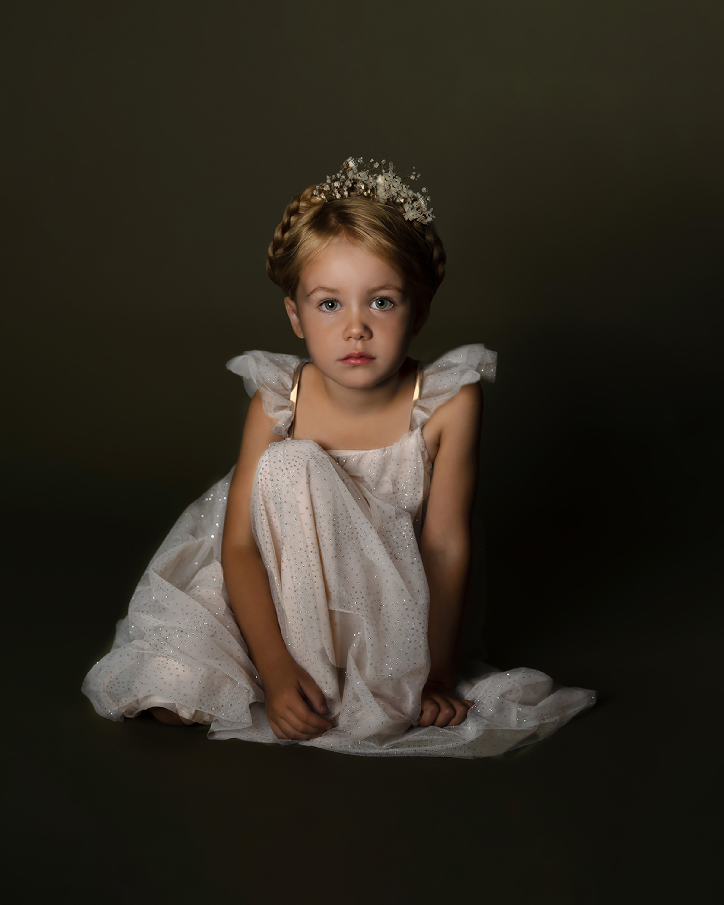 Portrett av jente i lys kjole som sitter på gulve