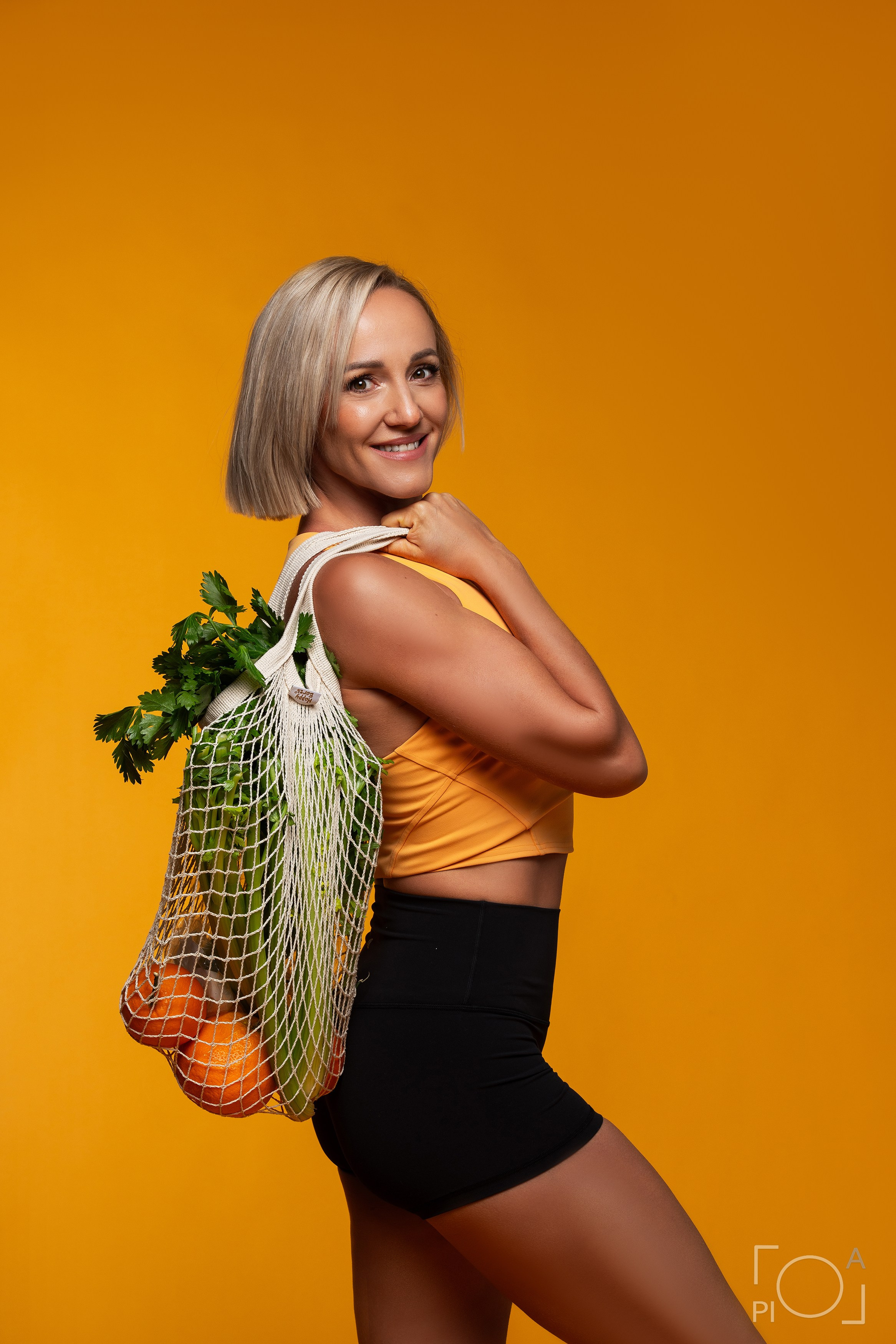 Studio photo shoot for fitness trainer. Yellow background. Blonde girl with a bob haircut.