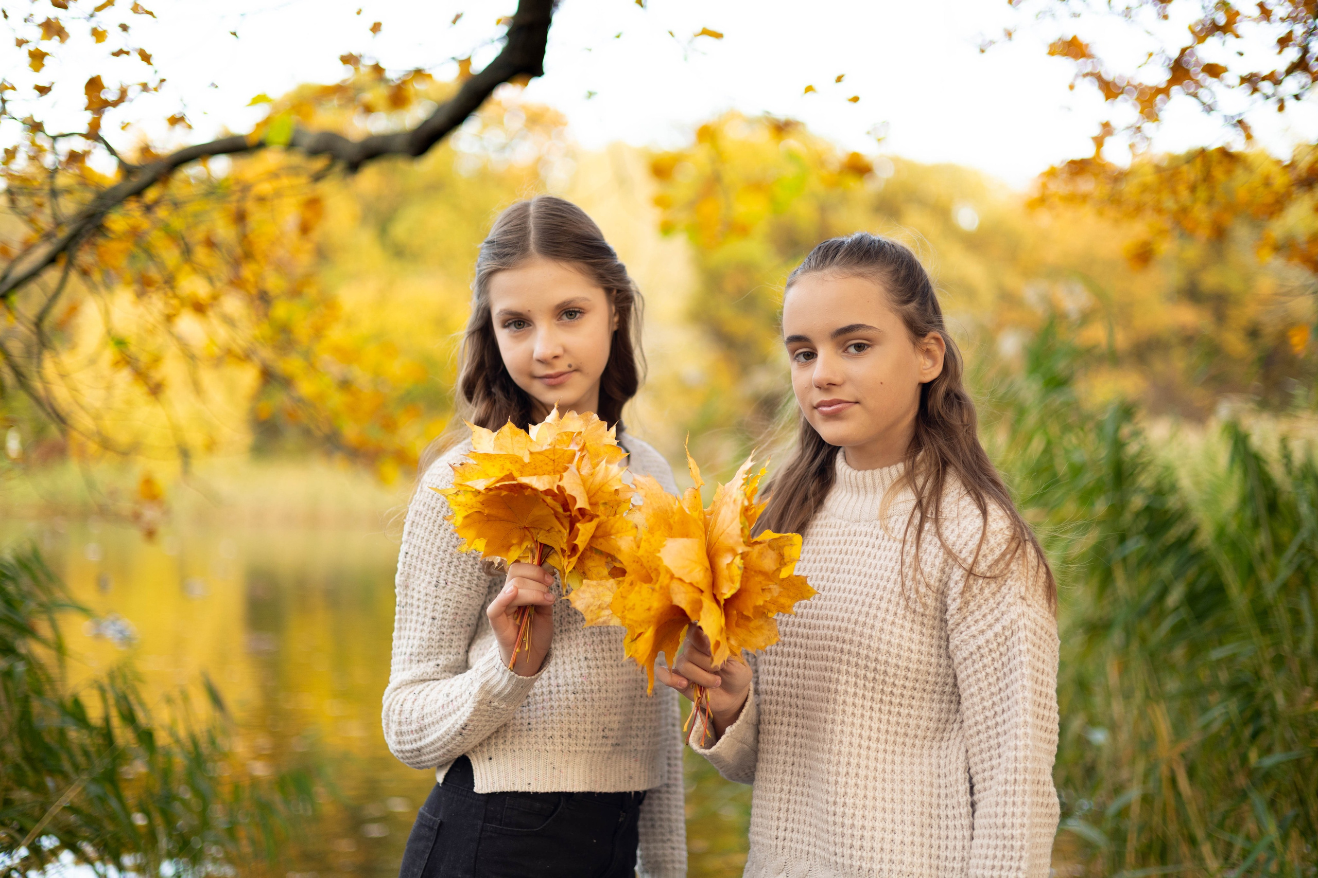 Девушки позируют фотографу в парке во время осенней фотосессии.