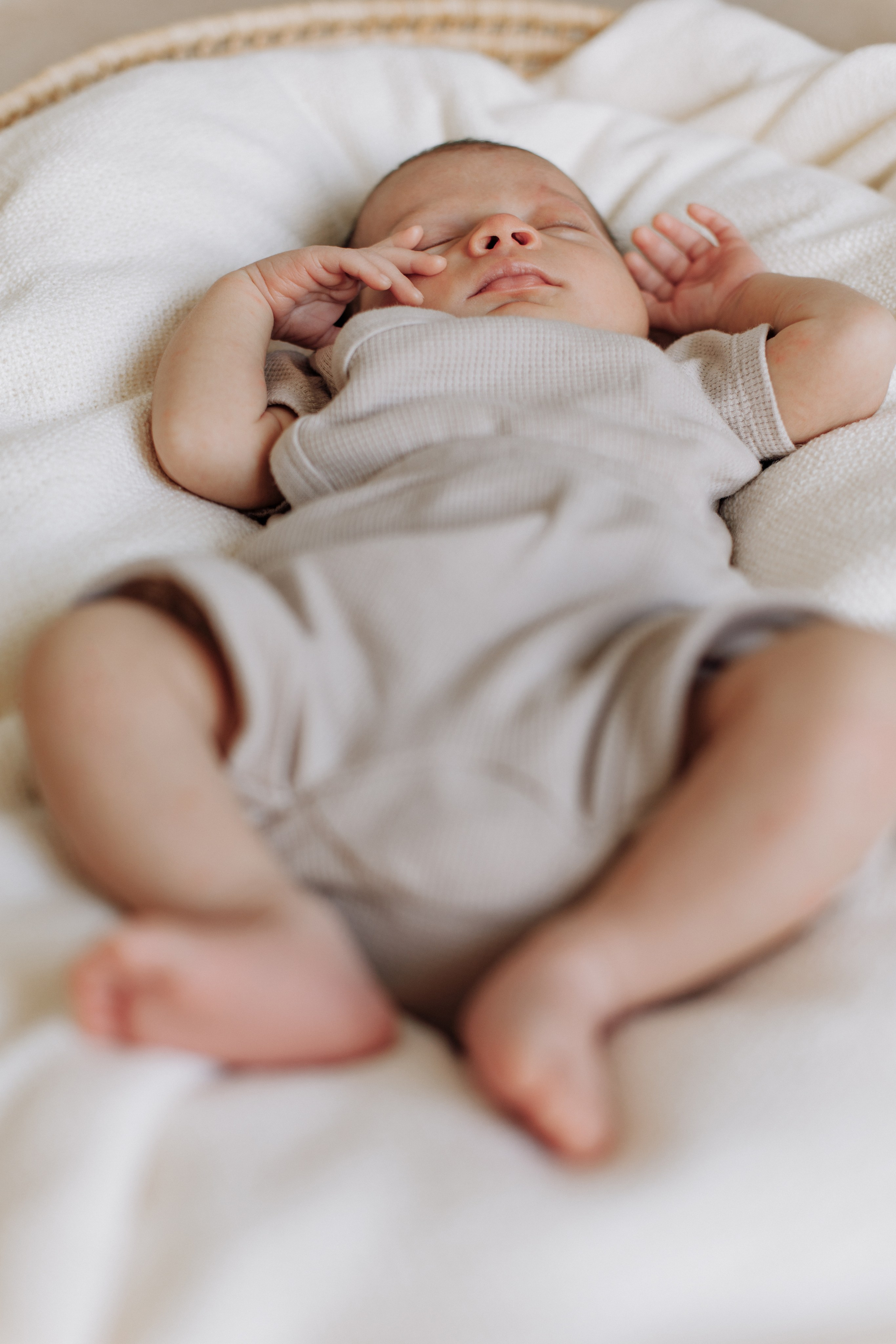 Baby schläft tief und fest während des Fotoshootings, seine kleinen Hände und Füße sind sichtbar.