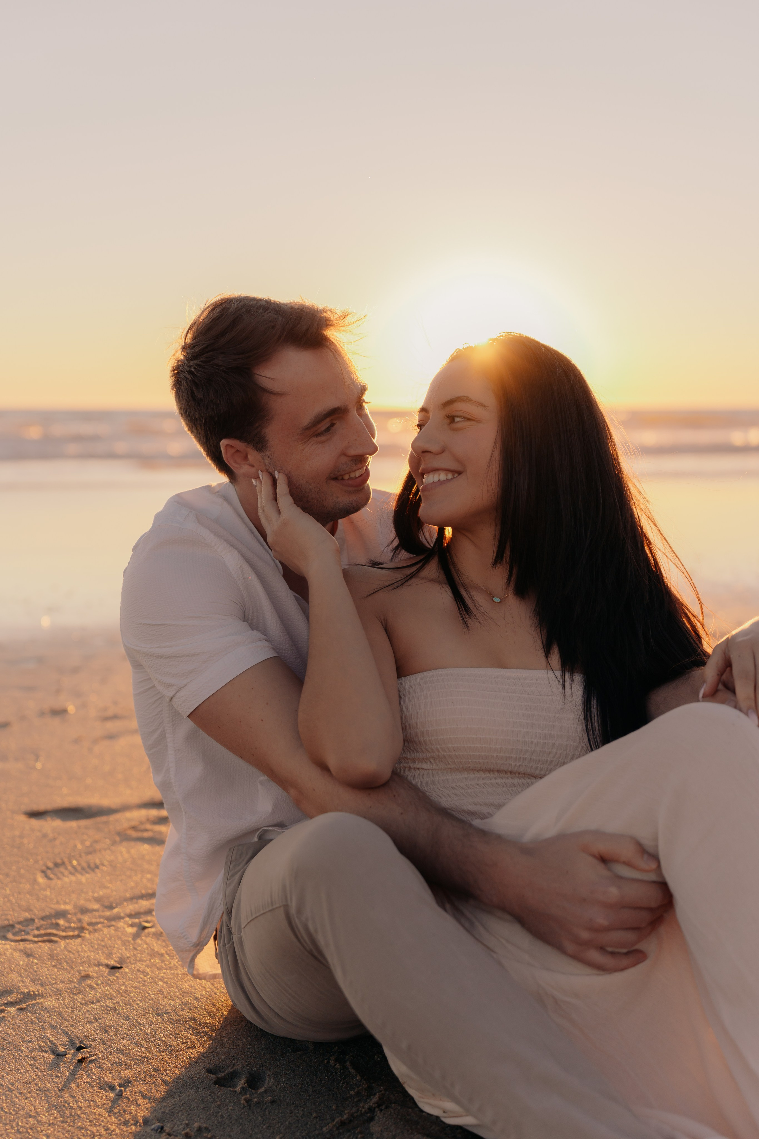 Candid beach engagement photos of a couple at sunset