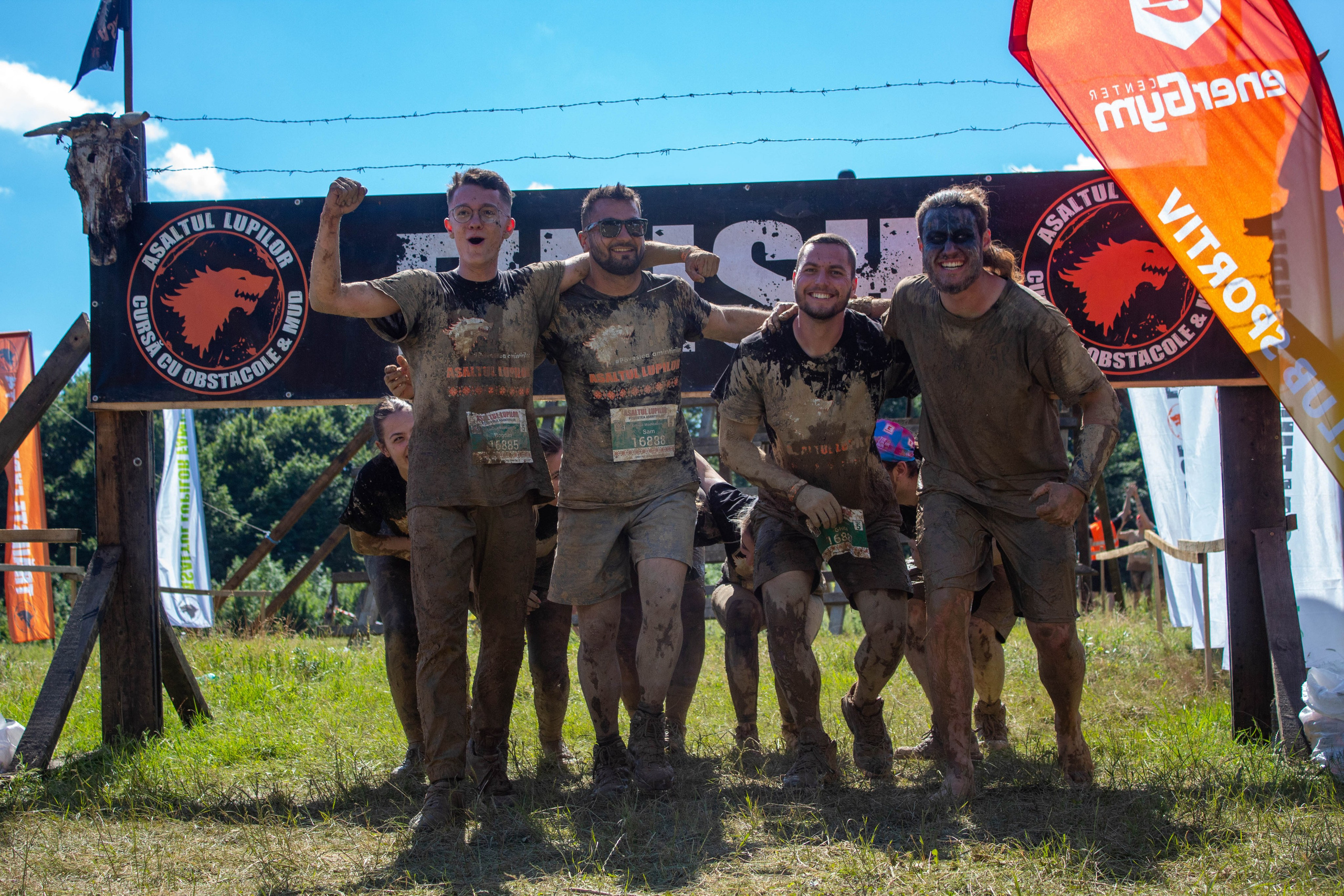 Mud-covered team posing with medals and banners at the end of a mud run competition.