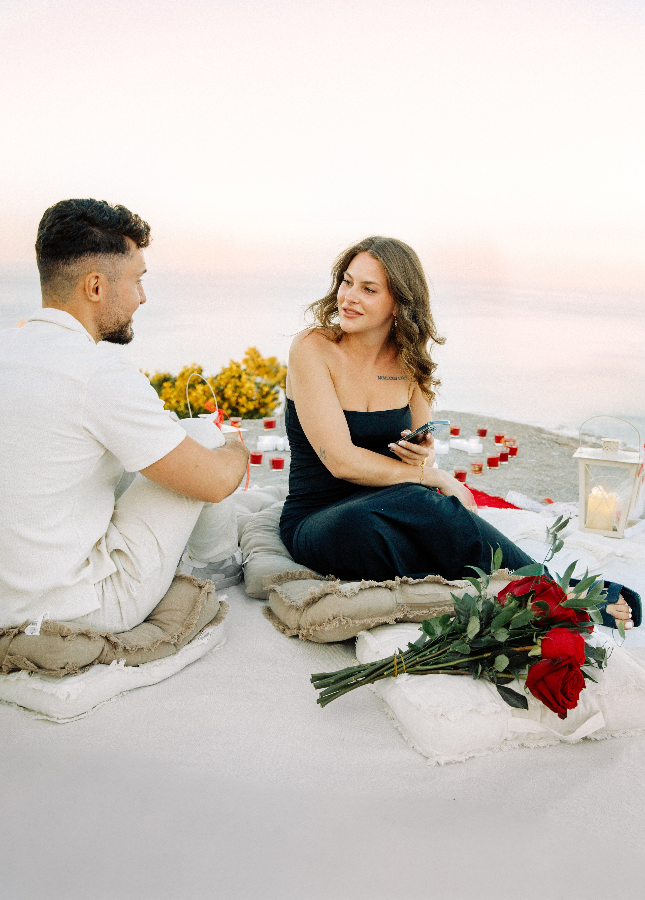 "Liebevoller Blickkontakt: Ein Paar auf dem Felsplateau des Profitis Ilias vor der Kulisse von Faliraki und dem Mittelmeer."