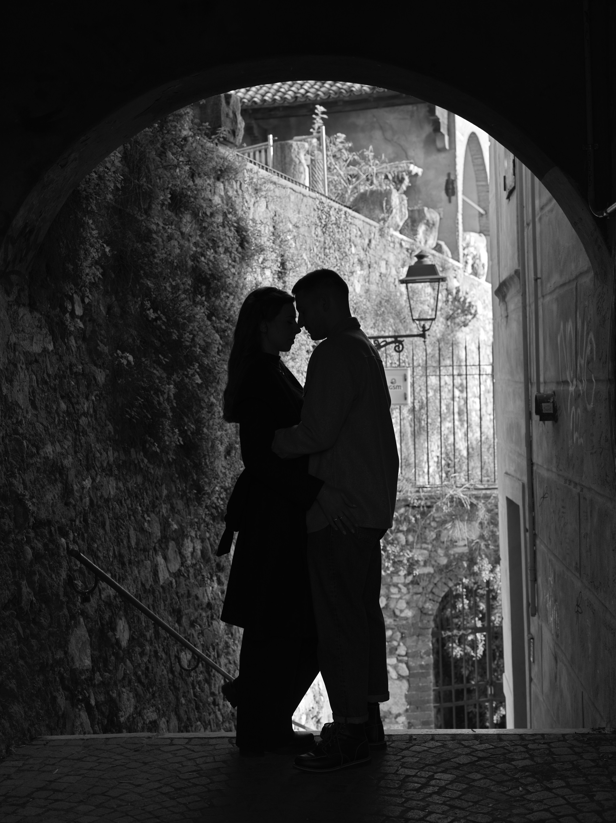 Romantic couple embracing in the archway near Castel San Pietro in Verona, surrounded by historic charm and affection