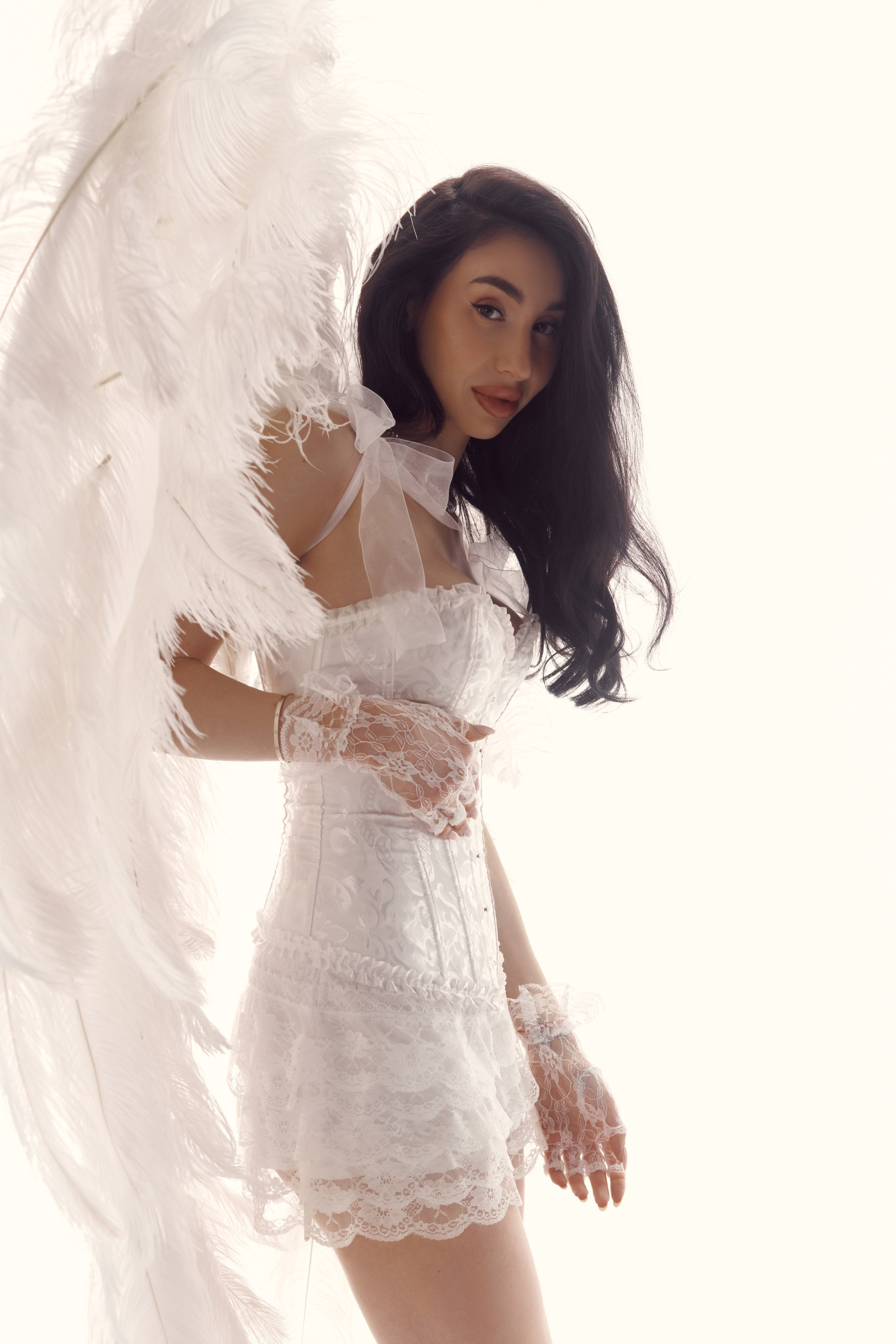 Minimalist studio portrait of Ester Rogovaya with wings on a white background using natural movement