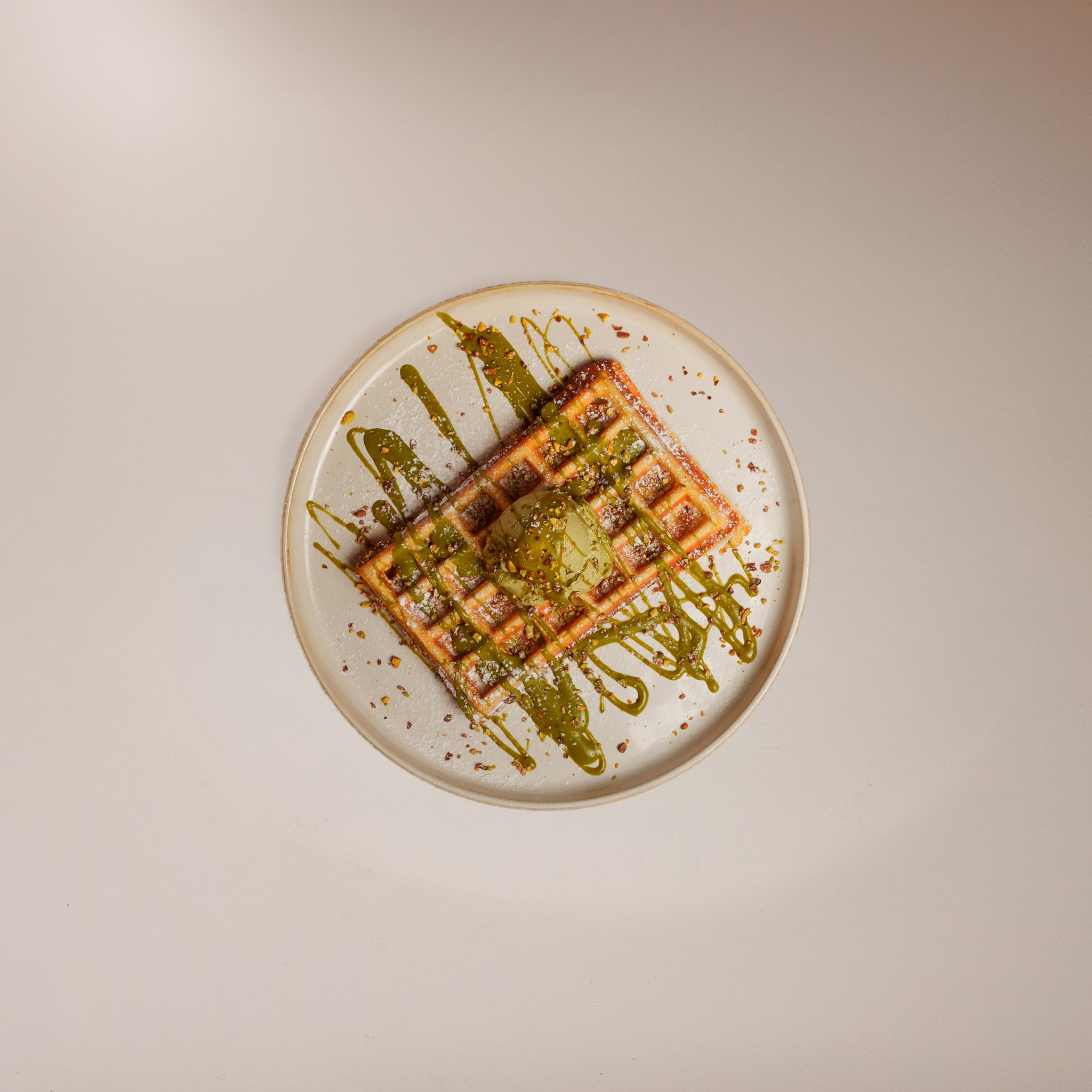 Fotografia de gastronomia vista de cima com um waffle decorado com pistácio, produzida em estúdio pela Khave Media