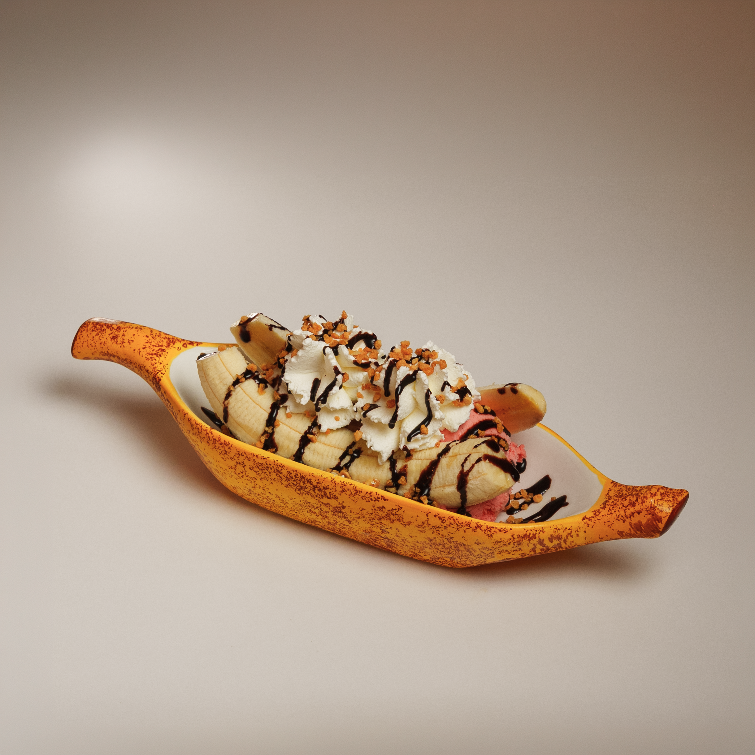 Fotografia de comida com uma banana split com chantilly numa taça temática sobre fundo neutro, captada pela Khave Media