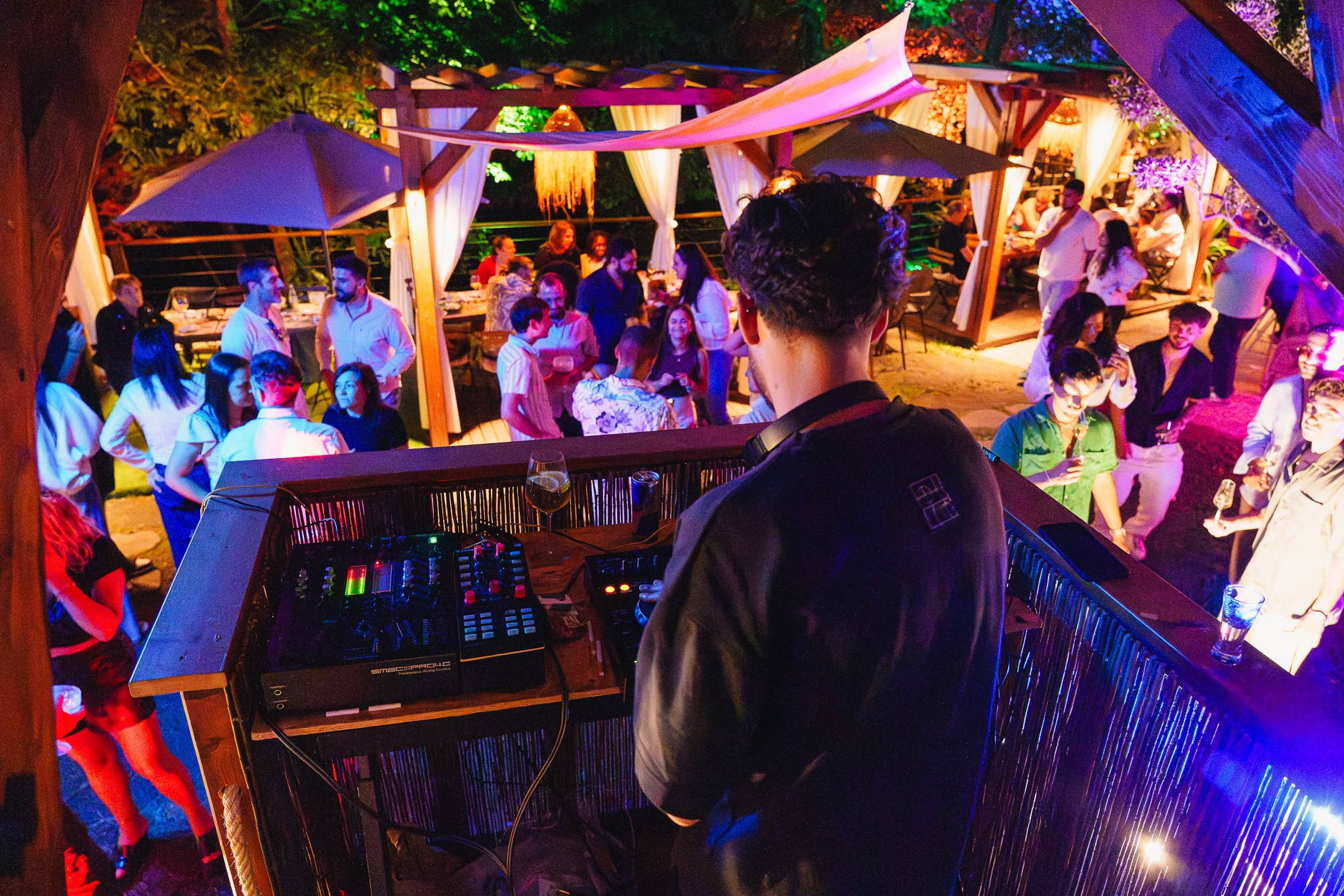 Fotografia de eventos e vida noturna de um DJ a atuar numa festa ao ar livre com luzes coloridas e público ao fundo, produzida pela Khave Media