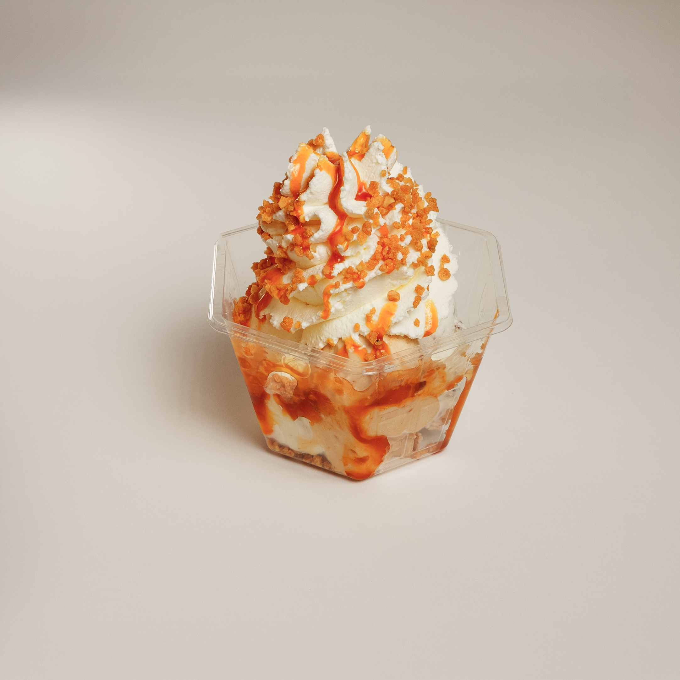 Fotografia de produto e sobremesa em estúdio de um copo de gelado com chantilly e calda de caramelo, captada pela Khave Media