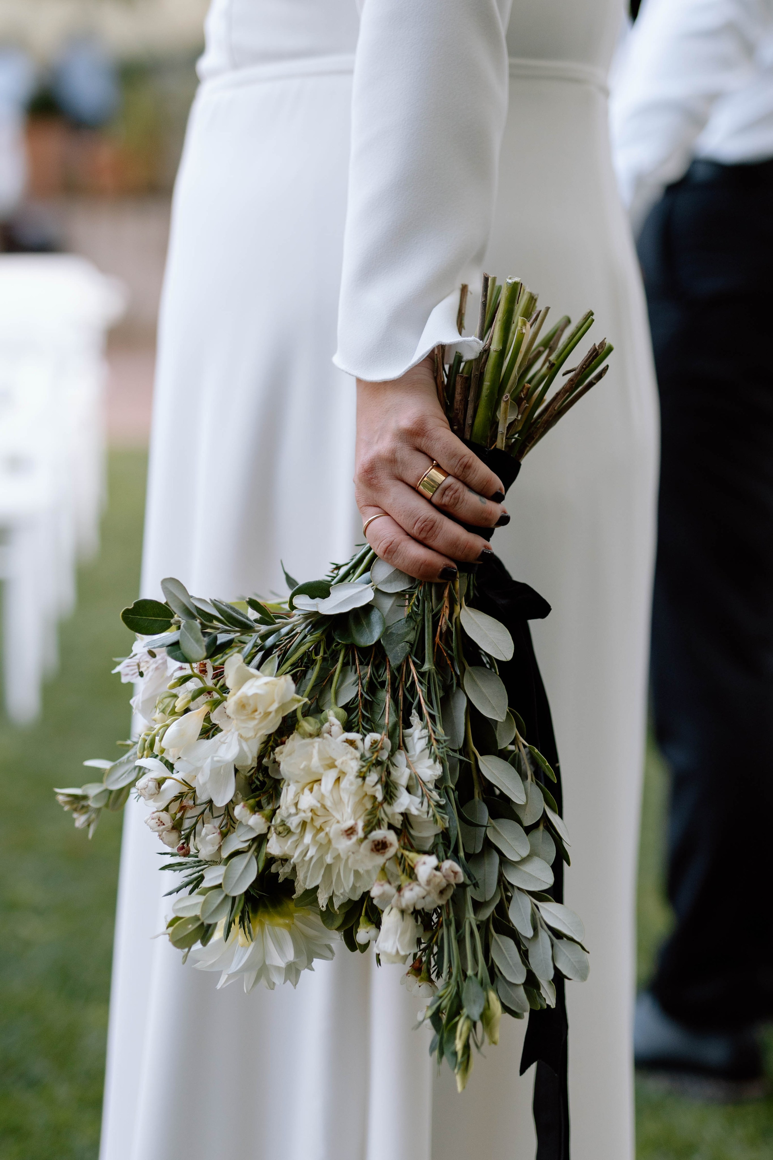 Detail of a bride holding a bouquet of flowers, white, green and black.