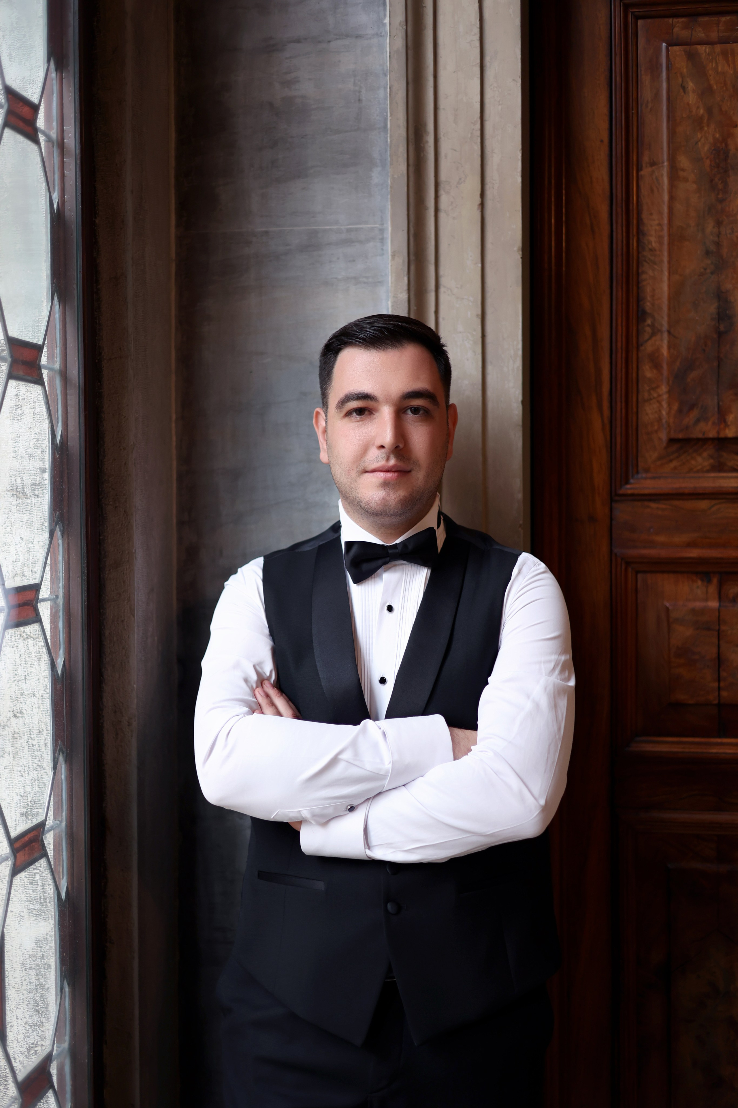 Armenian groom  in white dress standing in the serene courtyard of Aman Venice