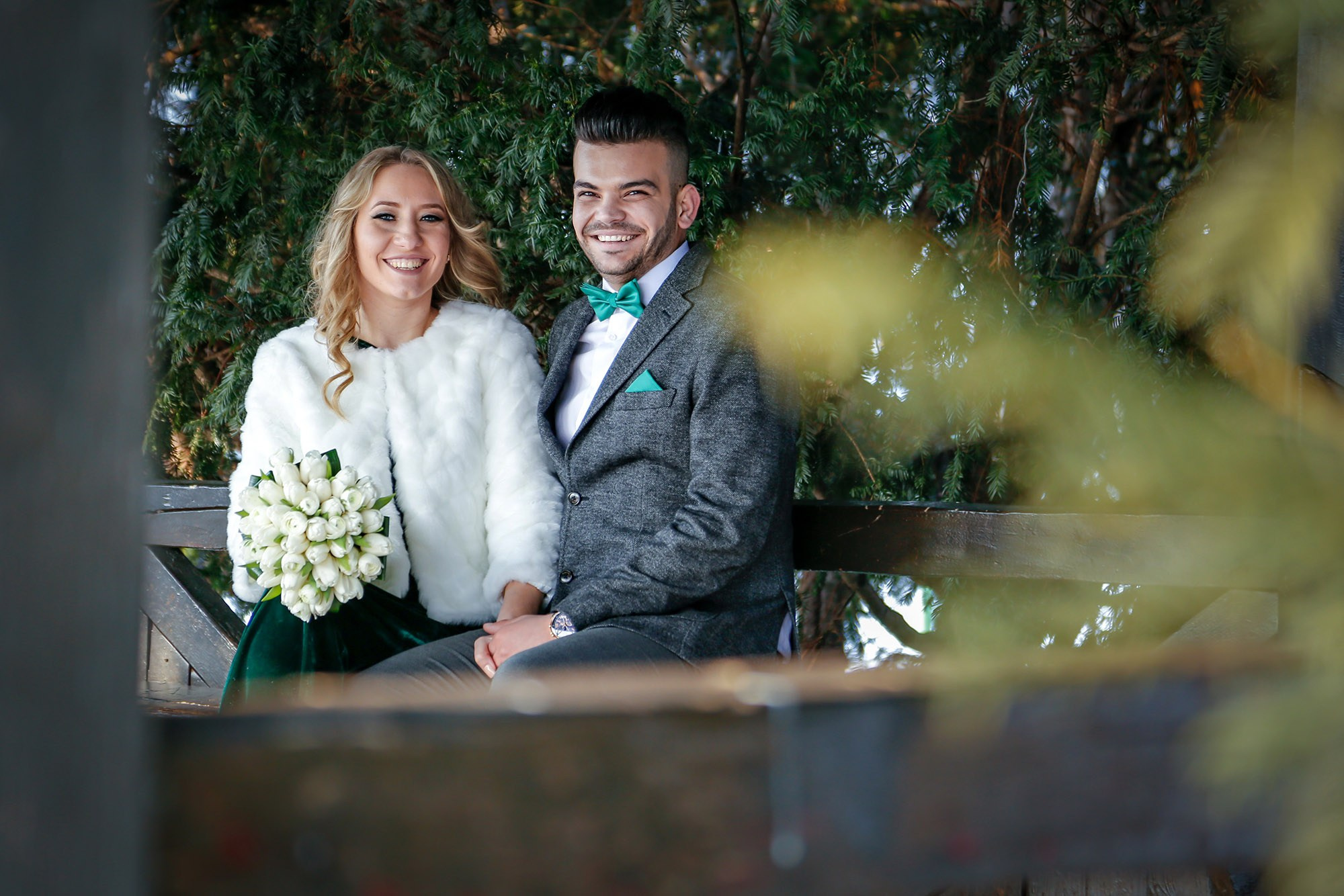 Bright portrait of the newlyweds smiling warmly inside the wooden gazebo during their civil wedding photo shoot.